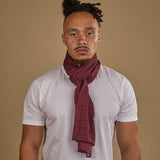 Close-up of model looking straight ahead wearing 'The Seattle' burgundy and blue geometric patterned wide bohemian scarf. Wrapped snugly around neck in a simple knot and paired with a white t-shirt.