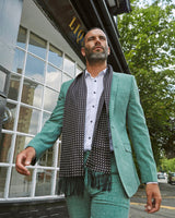 Modelling the 'Shinagwa' silk aviator scarf outdoors with the scarf draped around neck and paired with a casual mint-green suit.