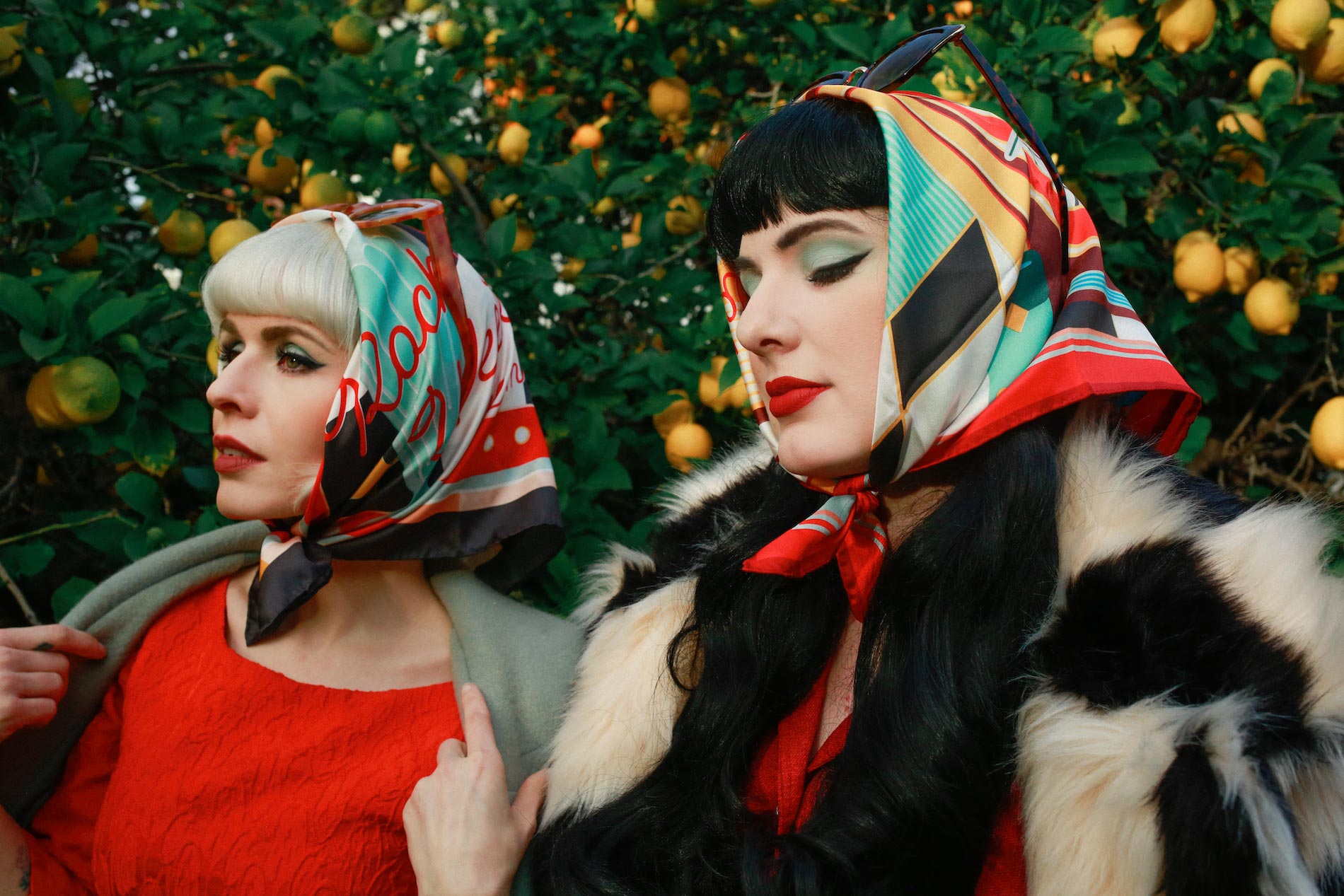 Two women in 1950's attire wearing matching retro headscarves from SOHO Scarves.