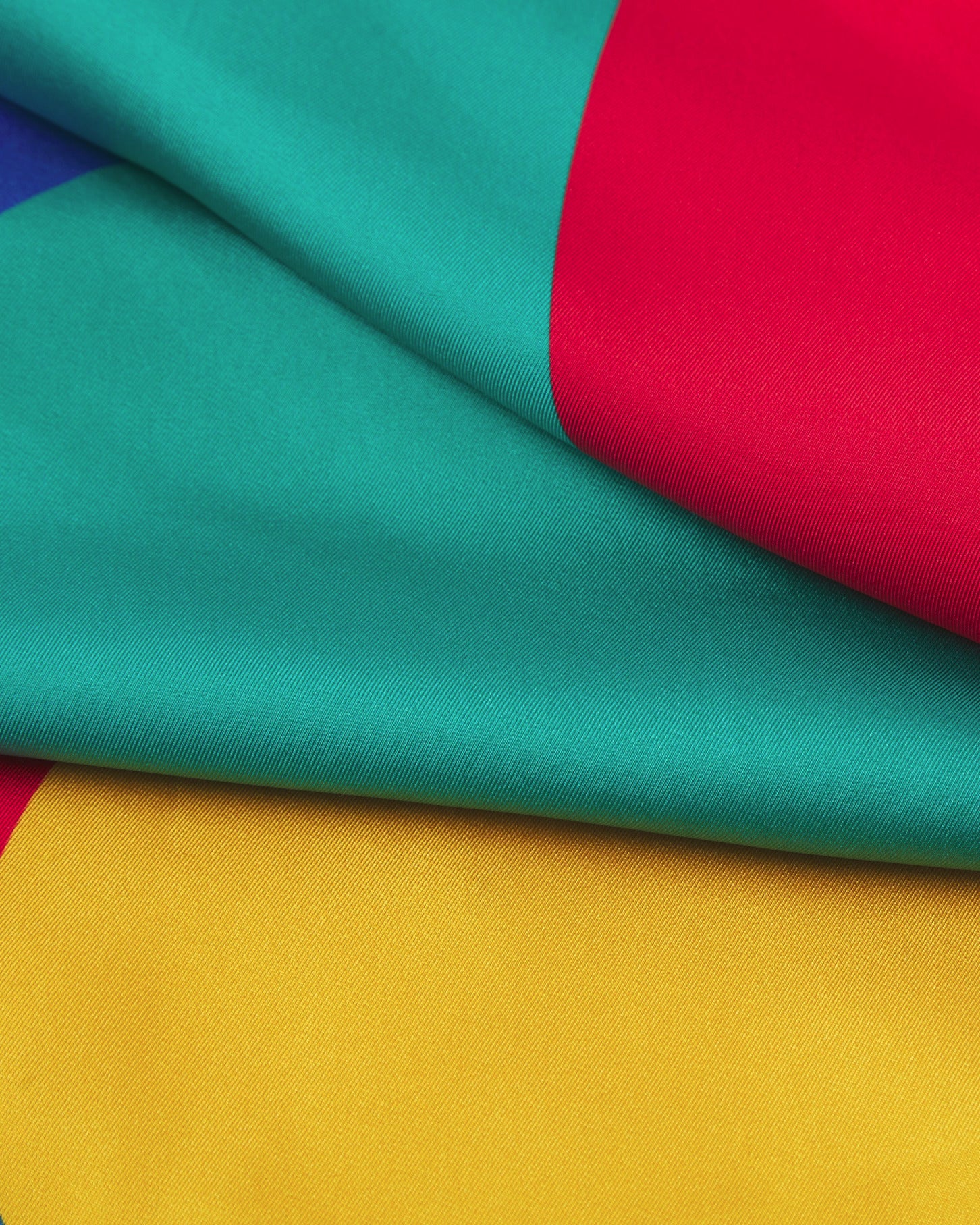 A ruffled close-up of the 'Munich' silk neckerchief, presenting a closer view of the Bauhaus-inspired, primary coloured patterns.