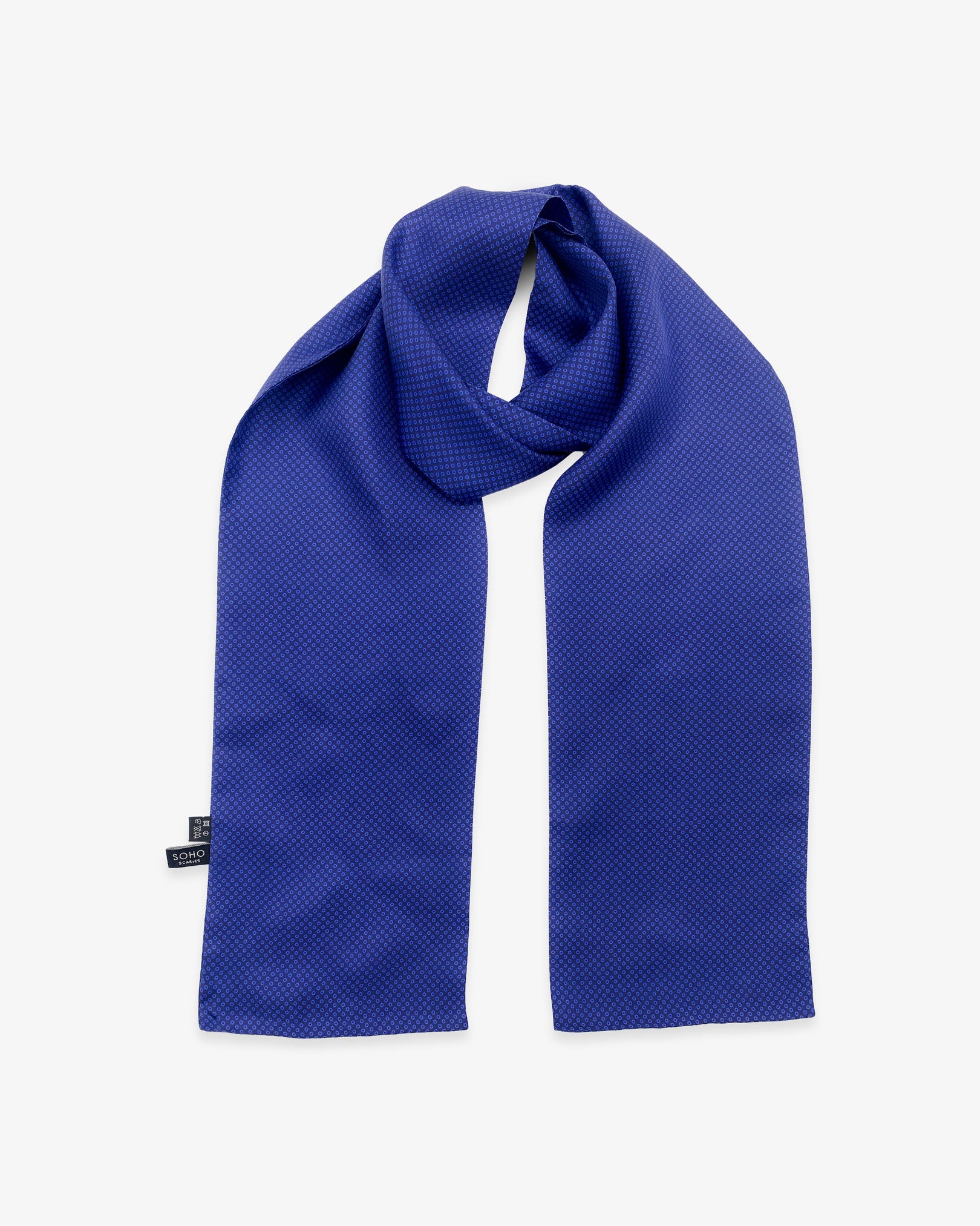 The 'Nakano' silk scarf looped with both ends parallel to effectively display the geometric small blue circles against a dark blue background.