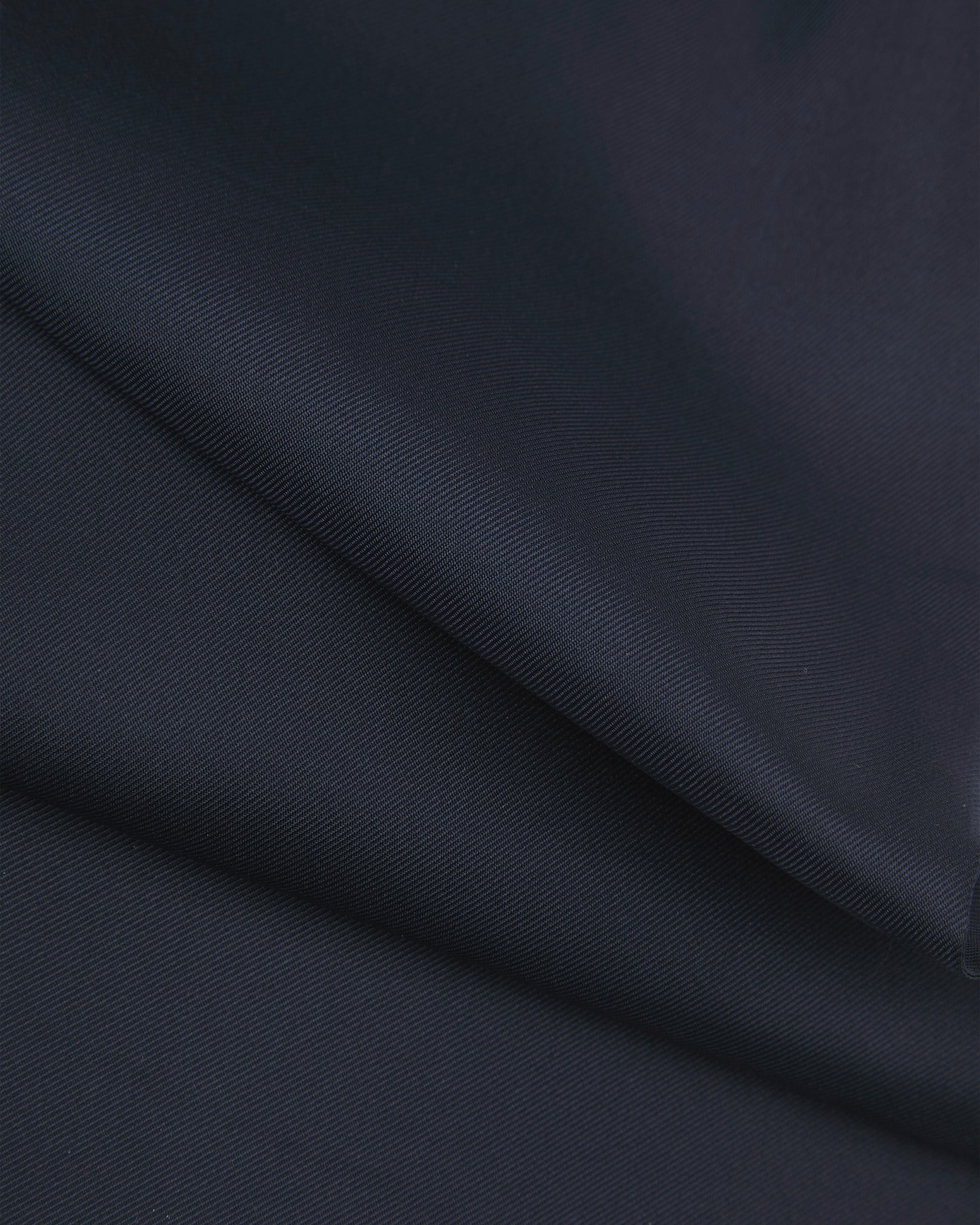 A ruffled close-up of the navy-blue silk aviator scarf, presenting the sheen of the fine silk material.