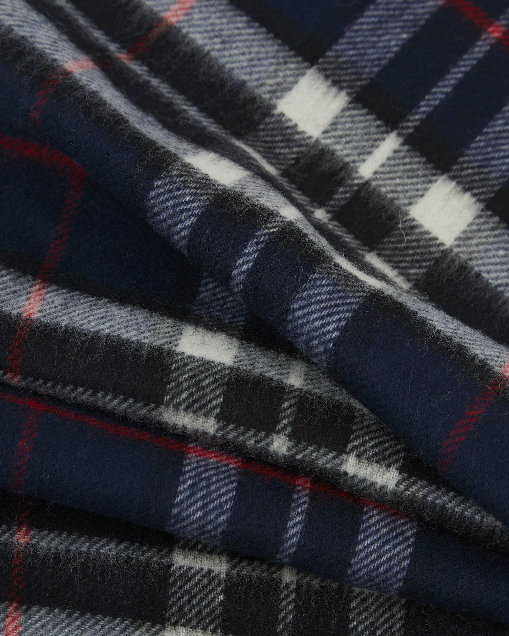 Ruffled close-up view of the UK-made, pure Merino wool 'Highlands' tartan in navy-blue scarf, presenting a closer view of the red, white, and black interlocking tartan pattern.