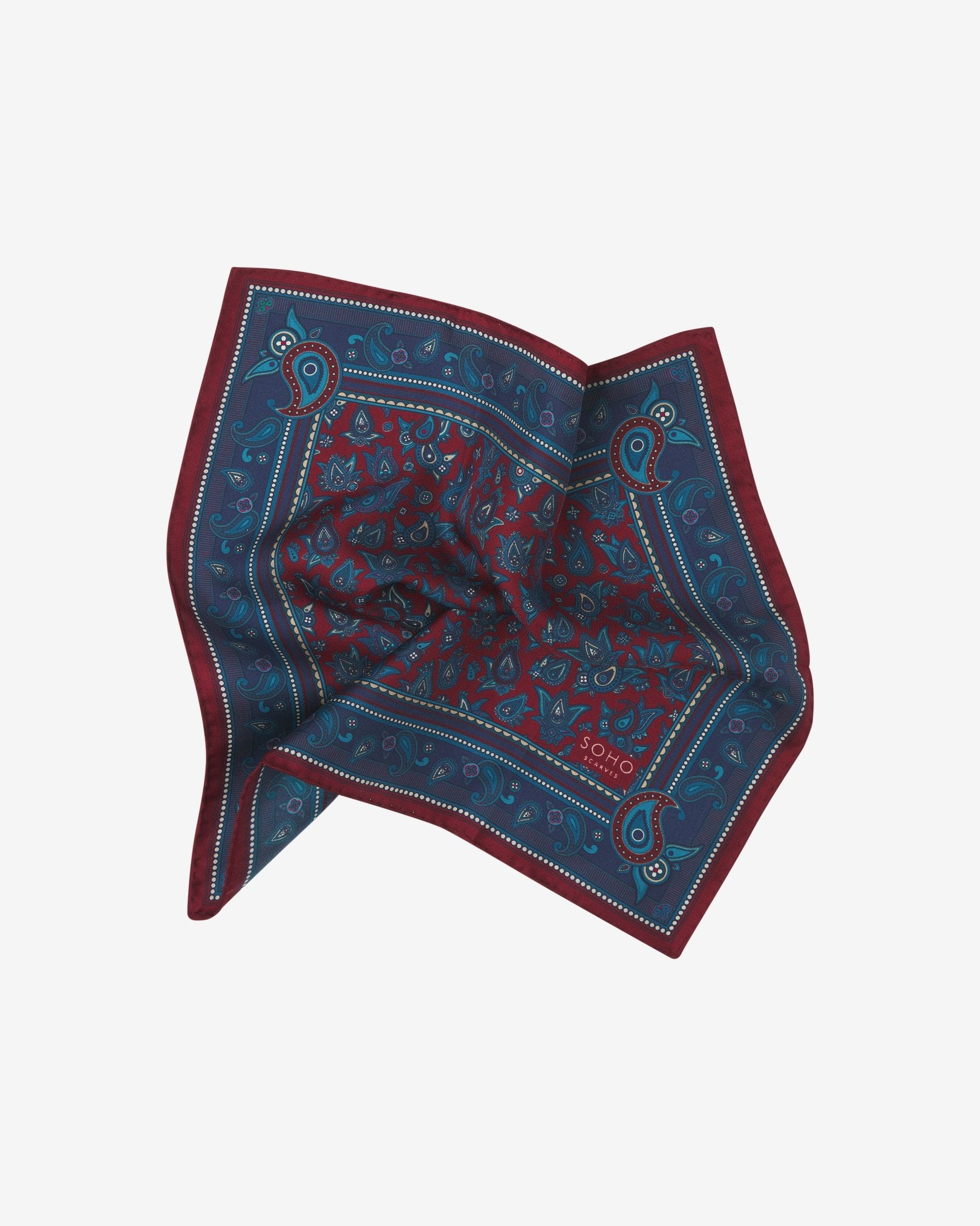 The 'Buttermere' pocket square pinched and twisted in the middle, presenting the blue and blue-green paisley patterns against the sheen of the fine silk material.