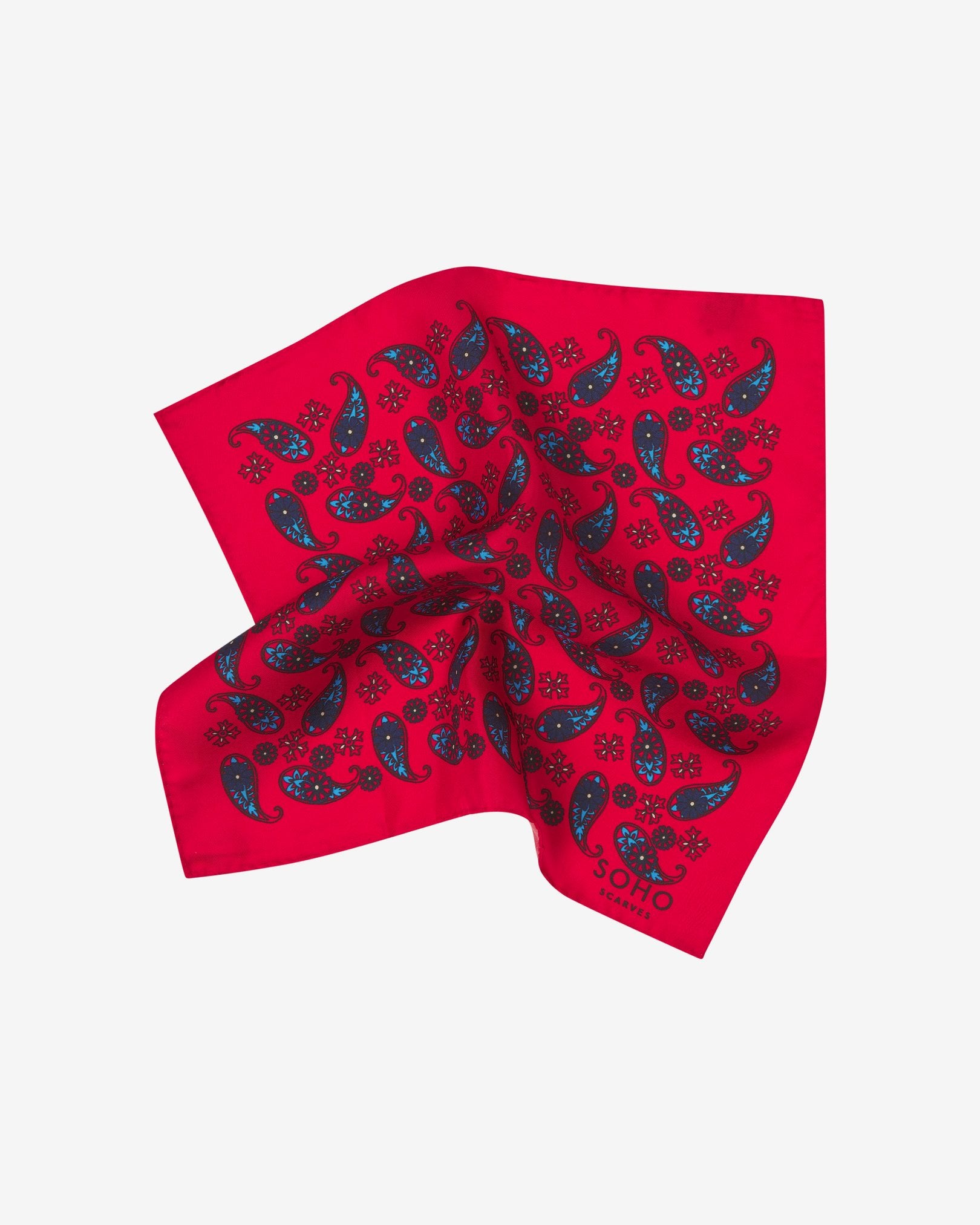 The 'Casablanca' silk pocket square pinched and twisted in the middle, showing showing blue paisley patterns on a bright red background.