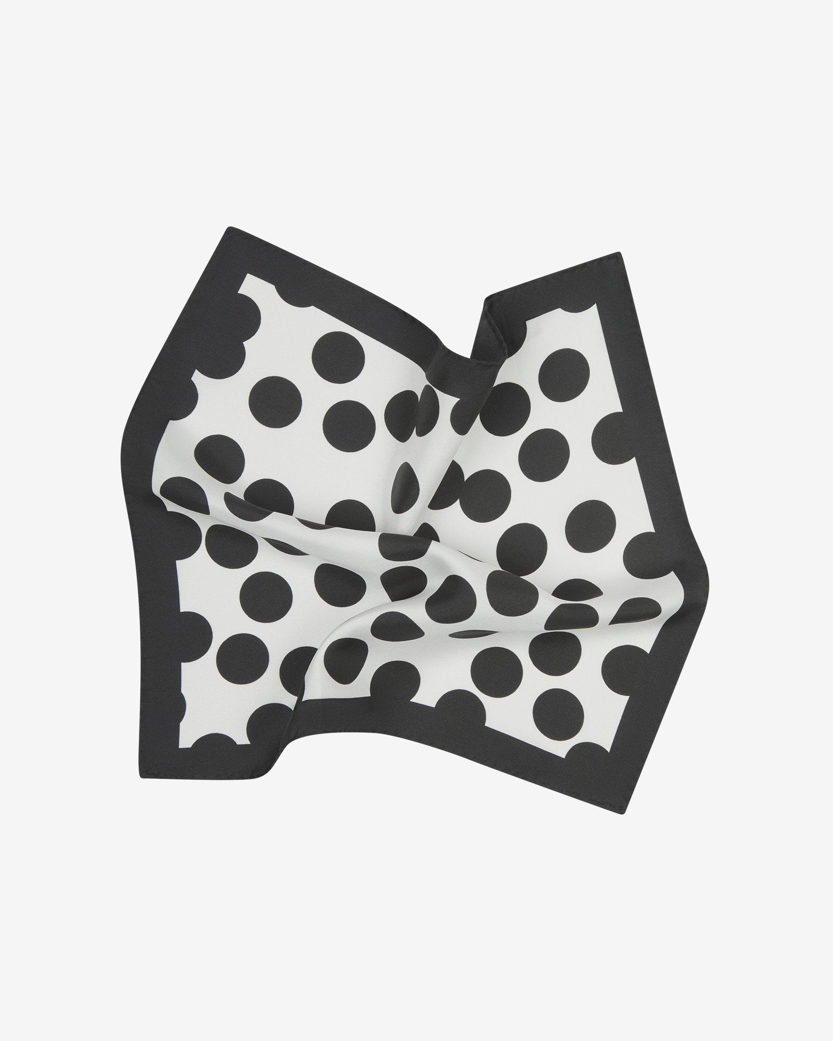 The 'Chaney' silk pocket square pinched and twisted in the middle, showing showing black polka dots on a white background, neatly framed with a black border.