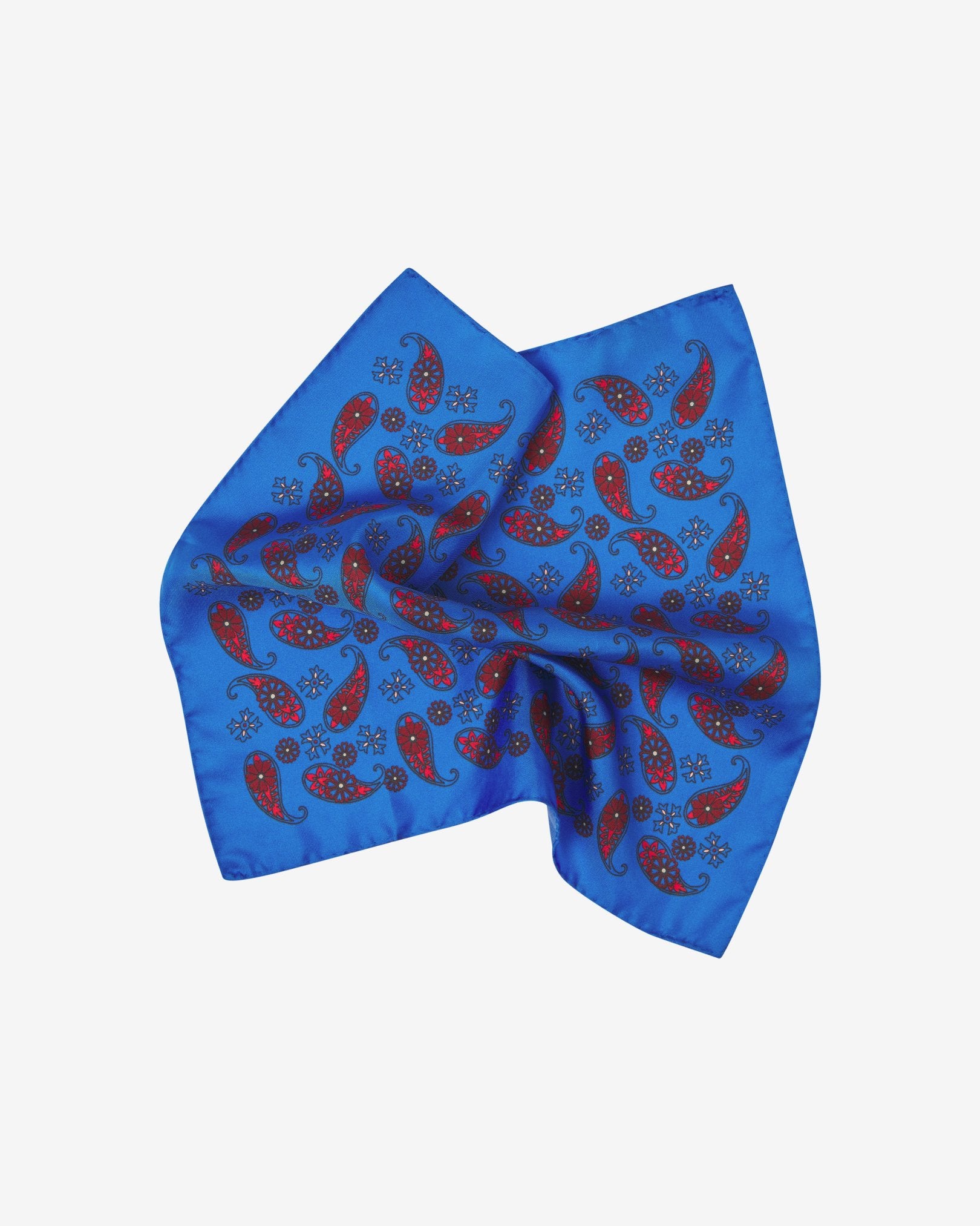 The 'Marrakesh' silk pocket square pinched and twisted in the middle, showing showing red paisley patterns on a bright blue background.