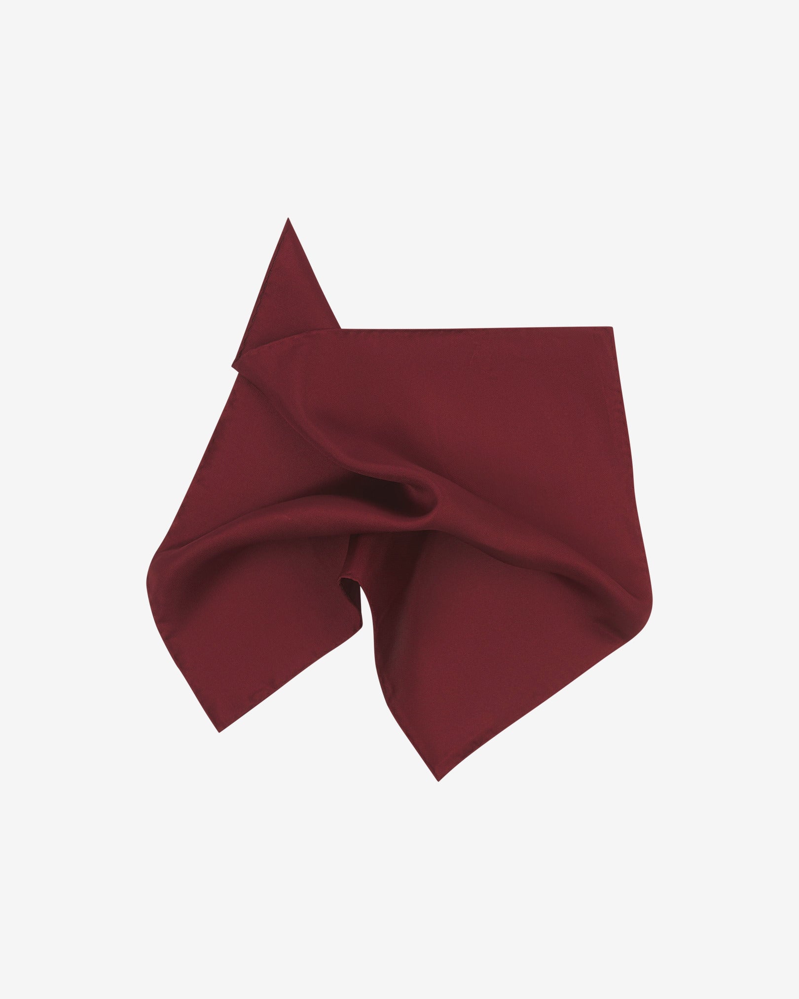 The plain, wine-red silk pocket square pinched and twisted in the middle, presenting the sheen of the fine silk material.