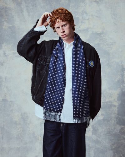 Demonstration of man wearing the 'Westminster' polka dot silk aviator scarf from Soho Scarves in navy blue.