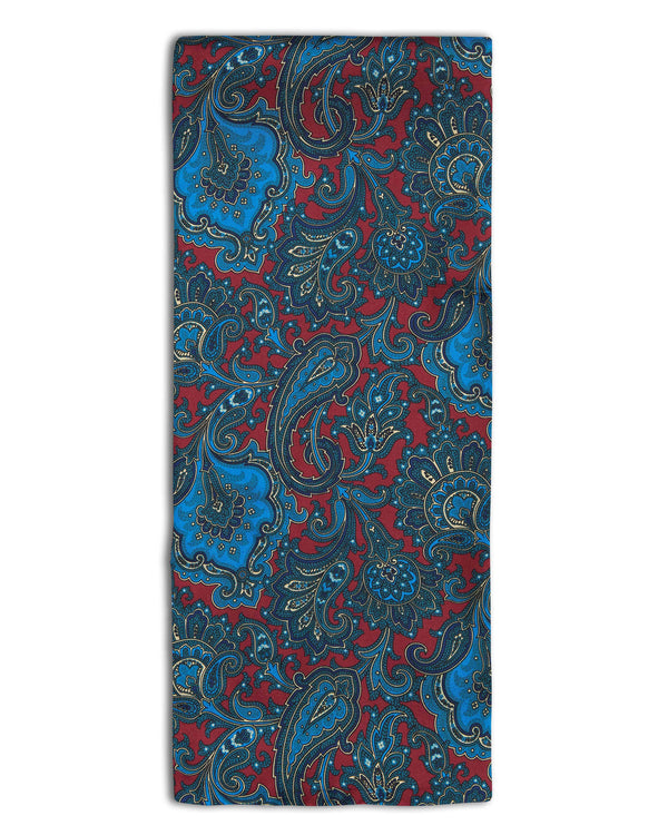 'The Dean' paisley silk scarf arranged in a rectangular shape, clearly showing the deep-red coloured fabric with blue patterns.