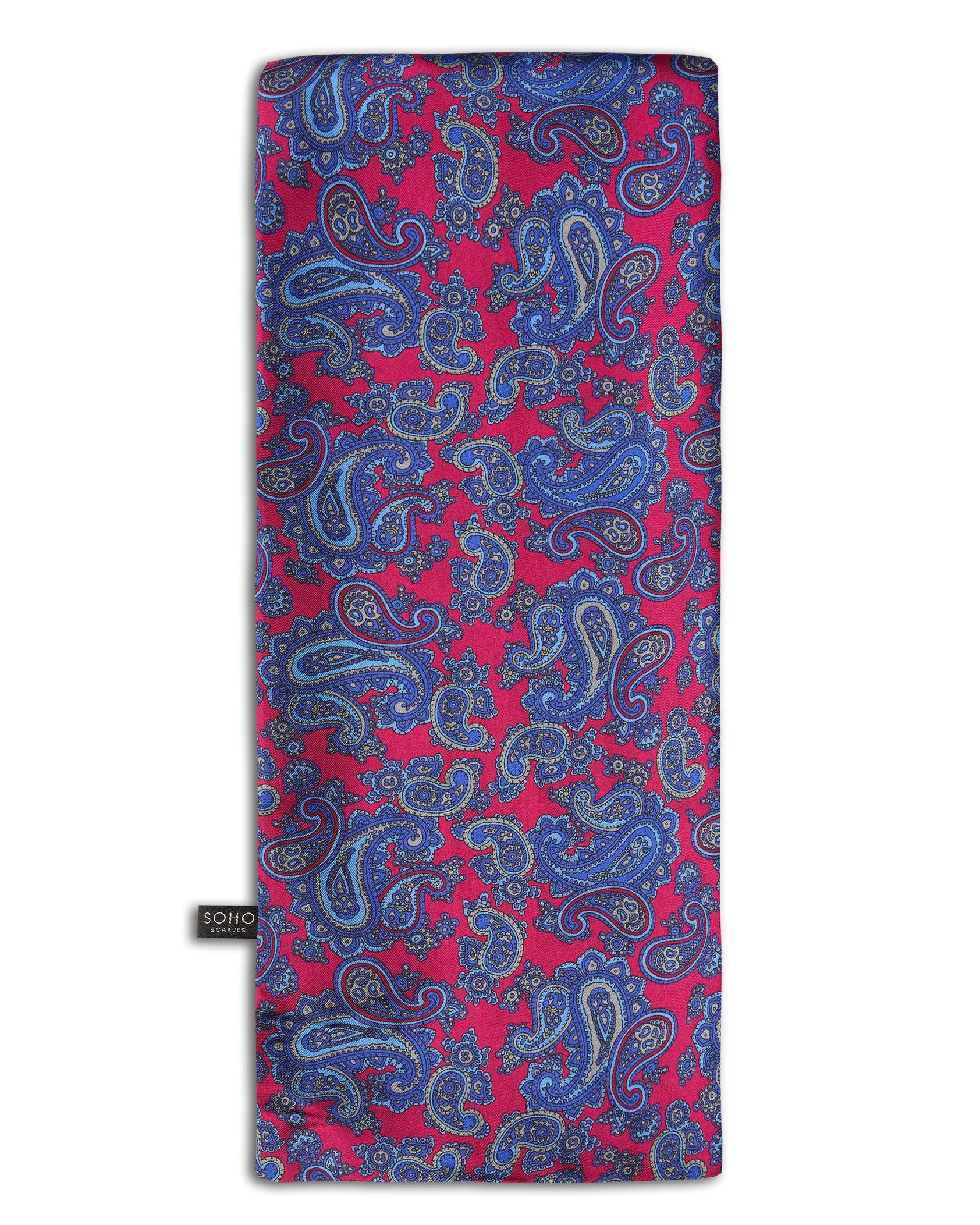 'The Kita' paisley patterned silk scarf arranged in a rectangular shape, clearly showing the fuchsia fabric with blue-violet paisley patterns and the 'Soho Scarves' branding label on the bottom left edge.
