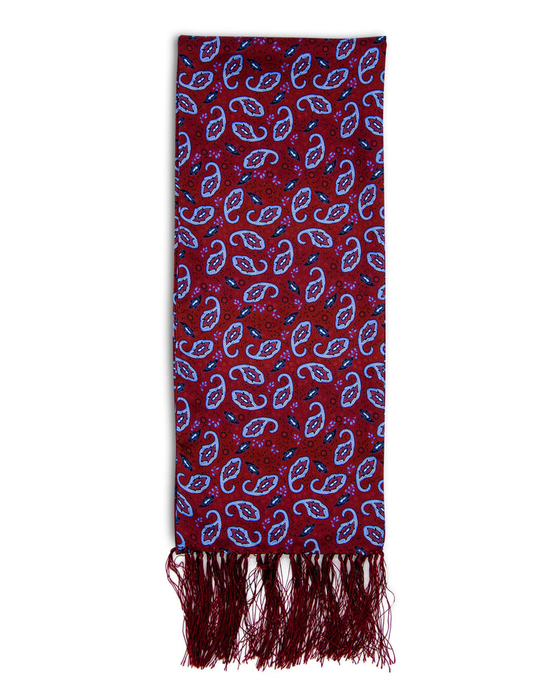 A flat view of 'The Palakta' silk aviator scarf. Clearly showing the small, pale blue stylised paisley swirls set on a burgundy ground with matching 3 inch fringe.