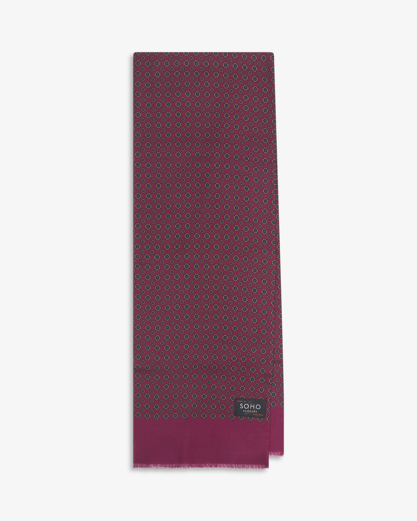 English-made silk and wool scarf arranged in a rectangular shape, displaying the repeating floral-inspired geometric forms with magenta eyelash fringing.