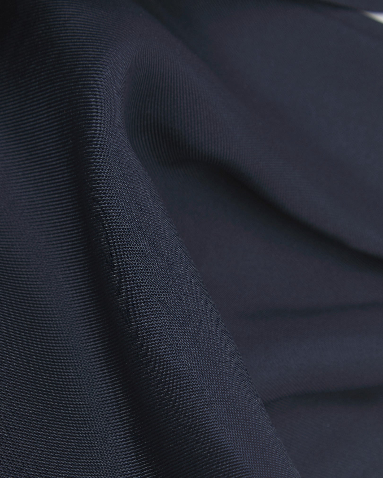 A ruffled close-up of the navy-blue double Ascot from Soho Scarves, presenting a closer view of the silk fabric and sheen.