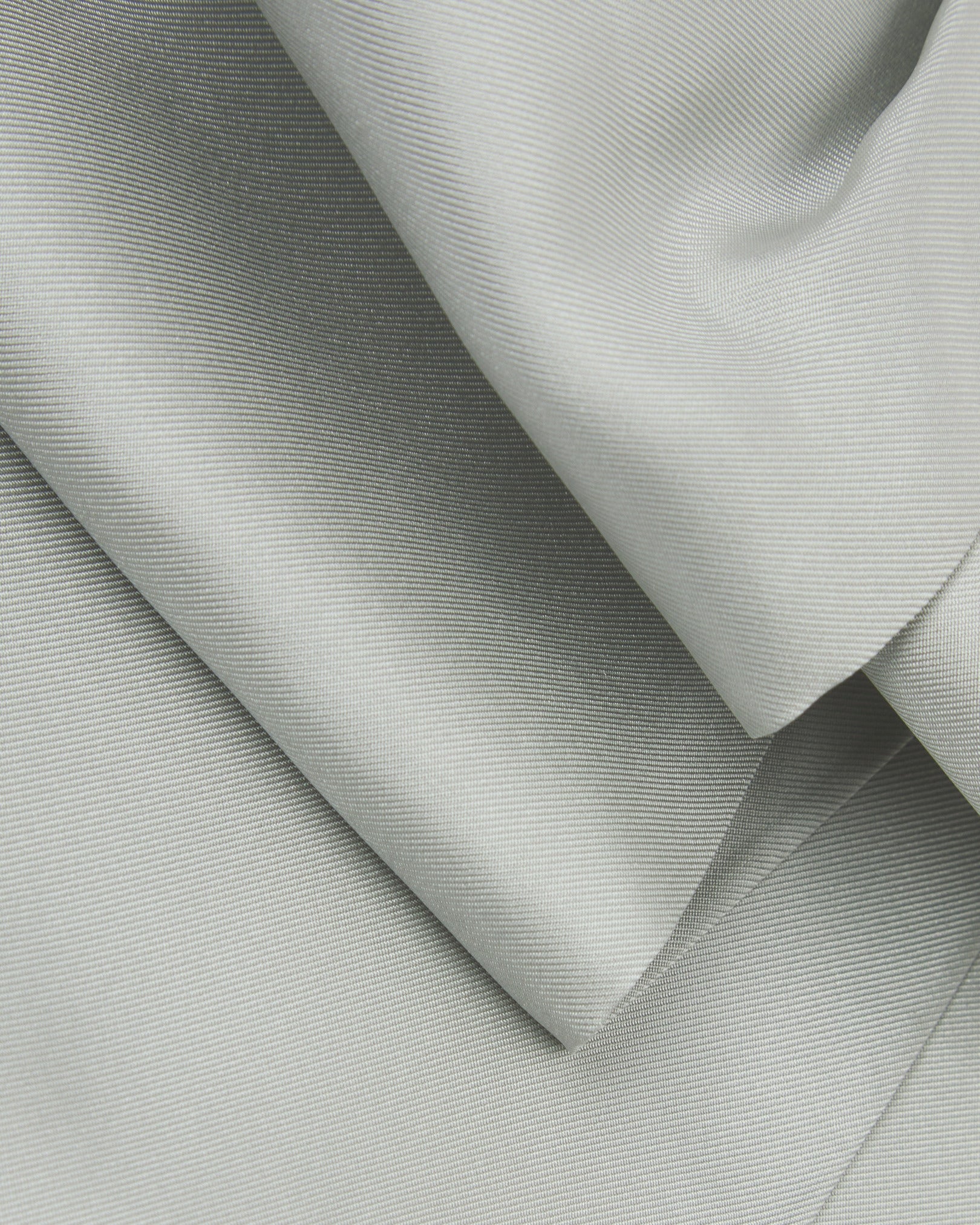 A ruffled close-up of the silver double Ascot from Soho Scarves, presenting a closer view of the silk fabric and sheen.