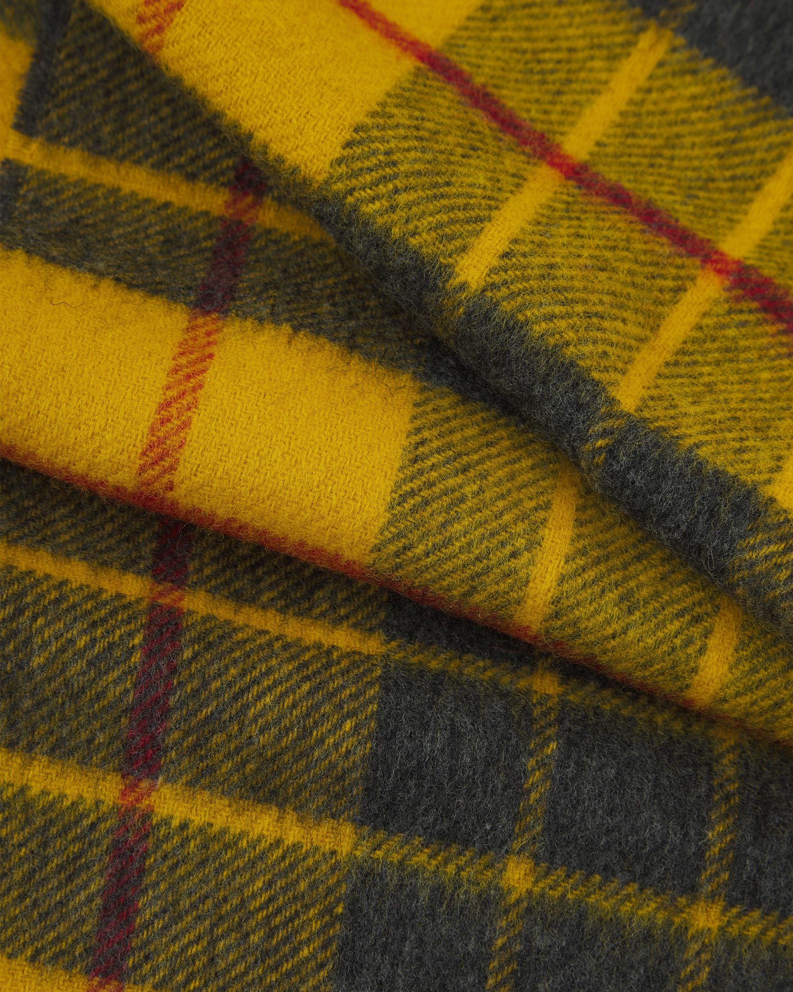 Ruffled close-up view of the UK-made, pure Merino wool 'Highlands' tartan in saffron scarf, presenting a closer view of the red and grey interlocking tartan pattern.