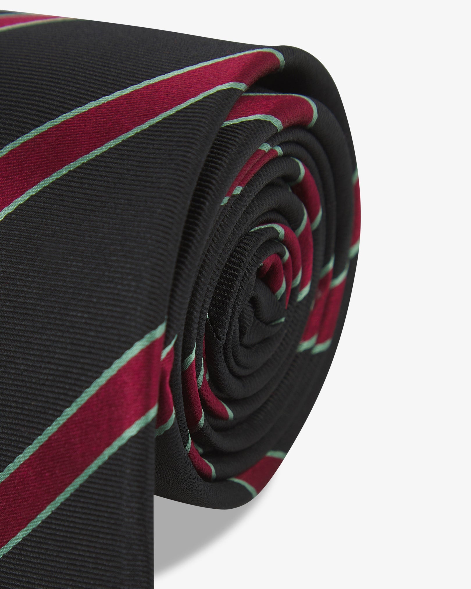 The 'Sanders Gardenia' silk neck tie neatly coiled with a clear view of the silk weave with red and teal stripes against a black background.