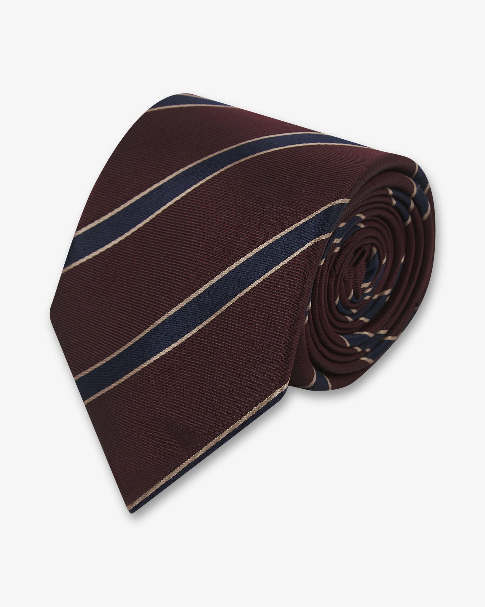 Focus on the tip of the 'Sanders Mahogany Haze' silk neck tie. Showing the gold and navy stripes and the remaining tie length neatly coiled.