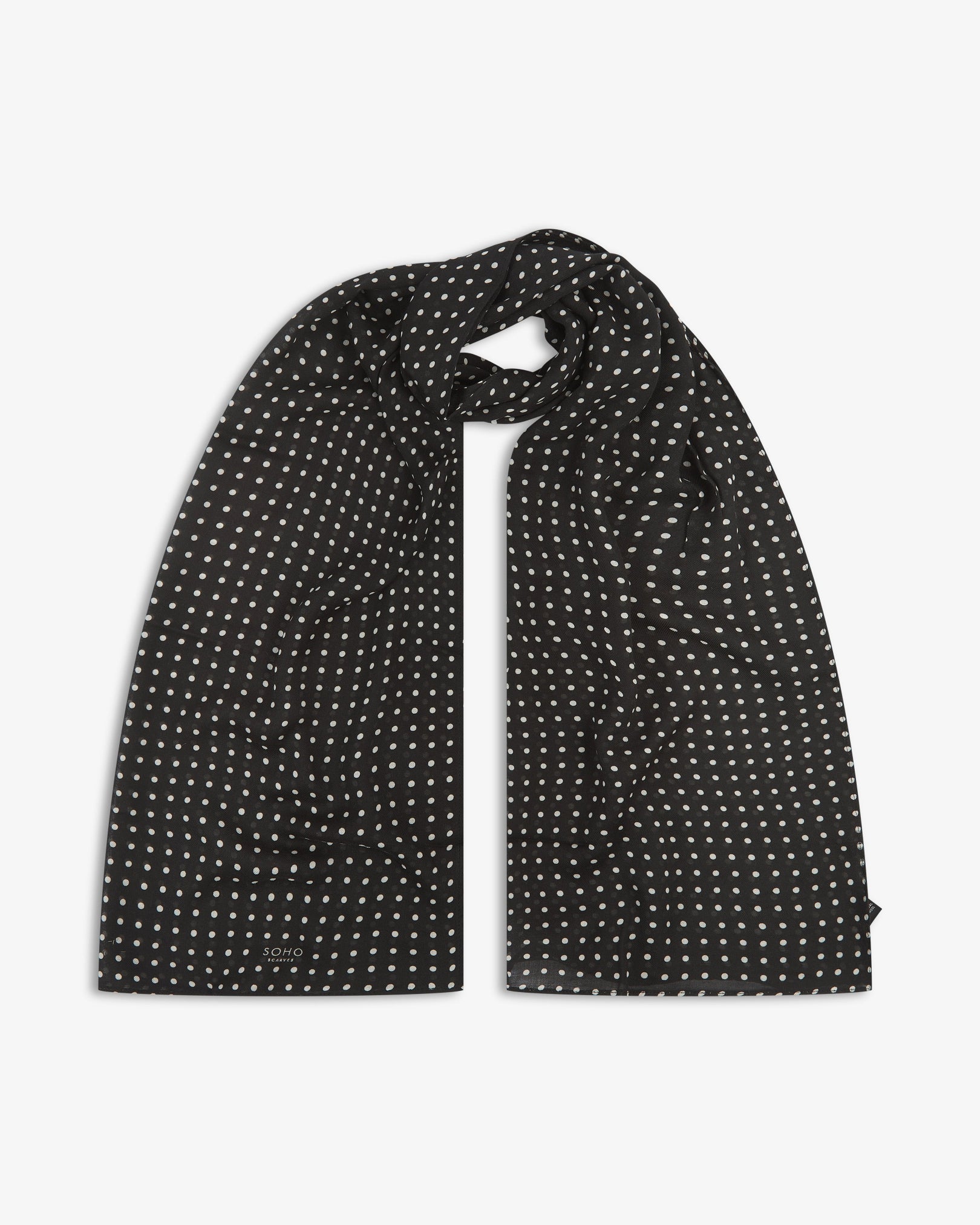 The Shinagawa bohemian wide scarf looped with both ends parallel, showcasing a classic pattern of white polka dots on a black background across the soft modal and wool blend fabric.