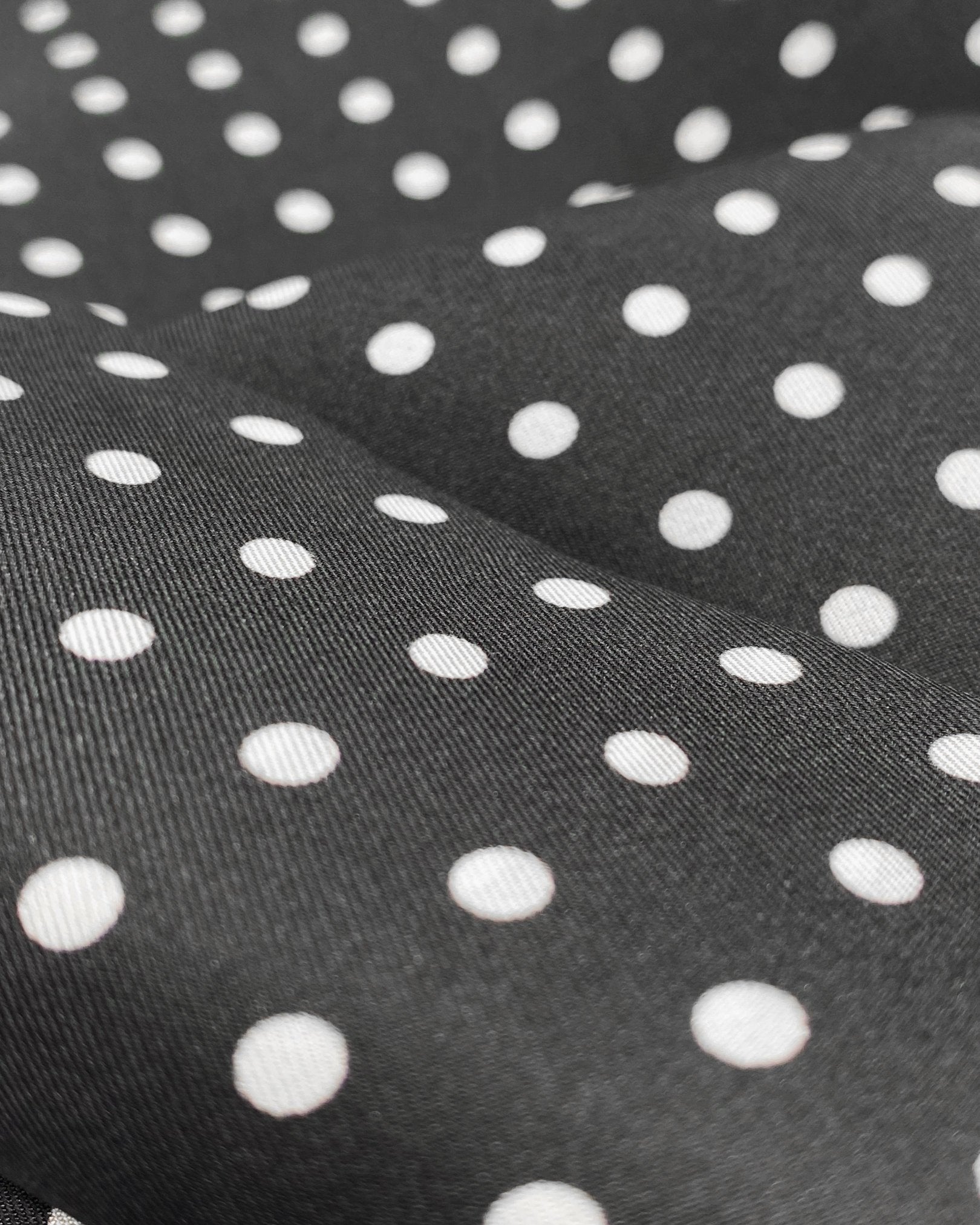 A ruffled close-up of the 'Shinagwa' silk neckerchief, presenting a closer view of the black silk fabric and the white polka-dot patterns.