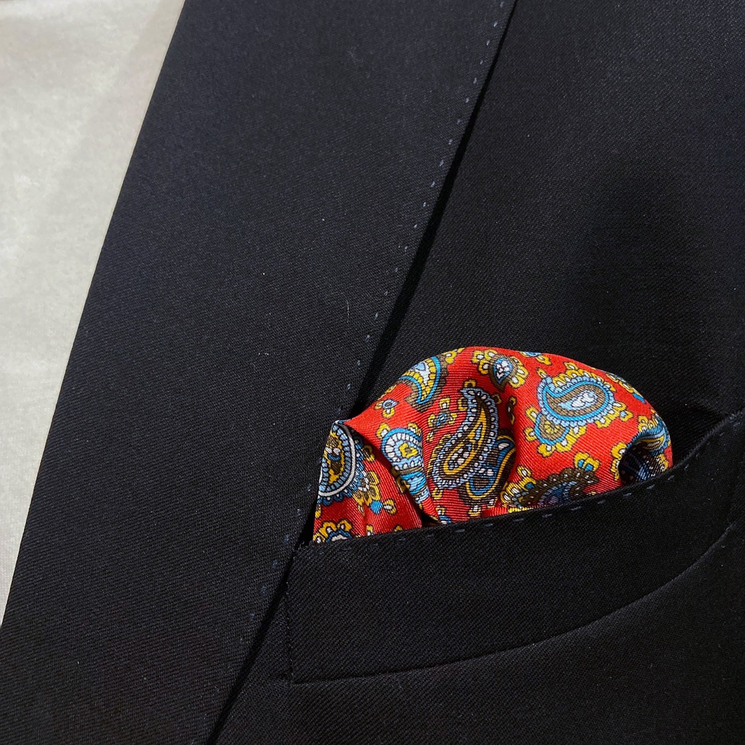 Close-up of the 'Shinjuku' silk pocket square in breast pocket of dark suit jacket.