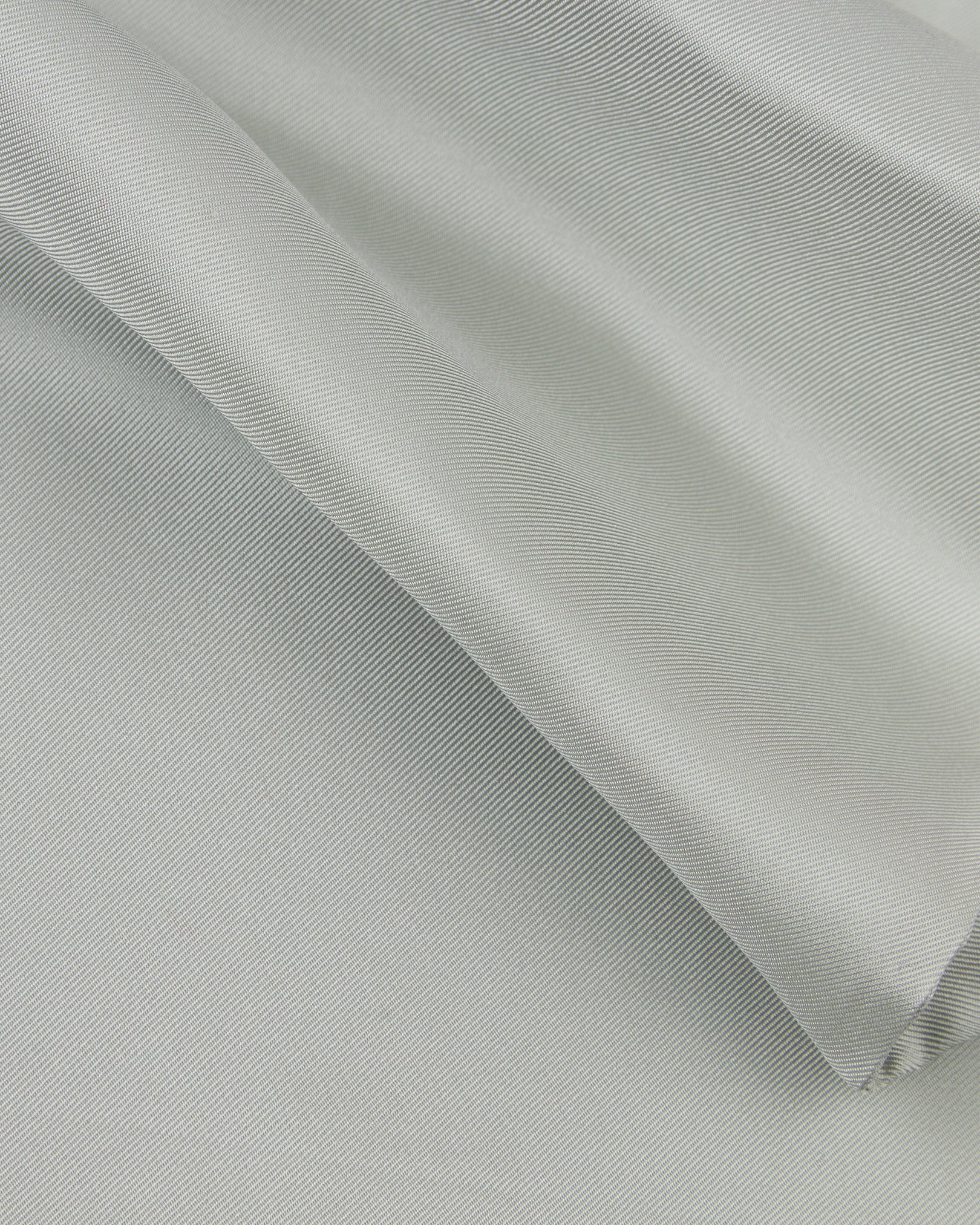 A ruffled close-up of the silver silk aviator scarf, presenting the sheen of the fine silk material.