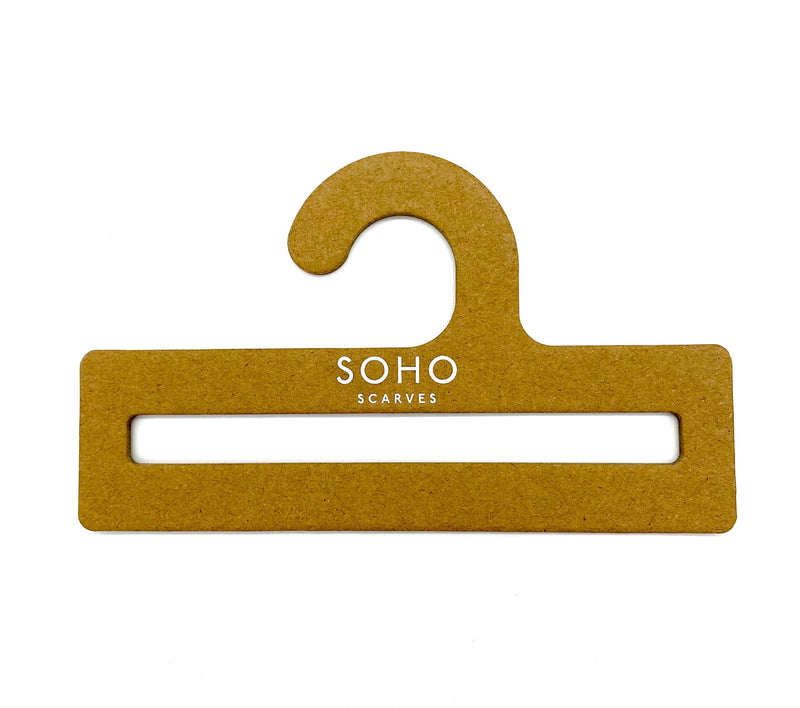 Full view of cardboard SOHO Scarves hanger on white background.