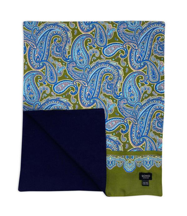 'The Abraham' wide dress scarf arranged in a square shape, clearly showing the olive green coloured fabric with blue patterns. The bottom-left quadrant is folded back to reveal the fine woollen lining underneath the pure silk exterior.