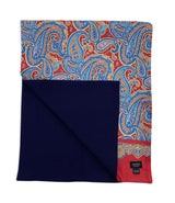Wide version of 'The Hedge' dress scarf arranged in a square shape with deep red fabric and blue paisley patterns. The bottom-left quadrant is folded back to reveal the fine woollen lining underneath the pure silk exterior.