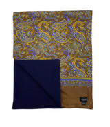 The wide version of 'The Whistler' multicoloured paisley wool-lined silk dress scarf on a brown background. Arranged in a square shape with a corner folded back to reveal the fine navy woollen underside.