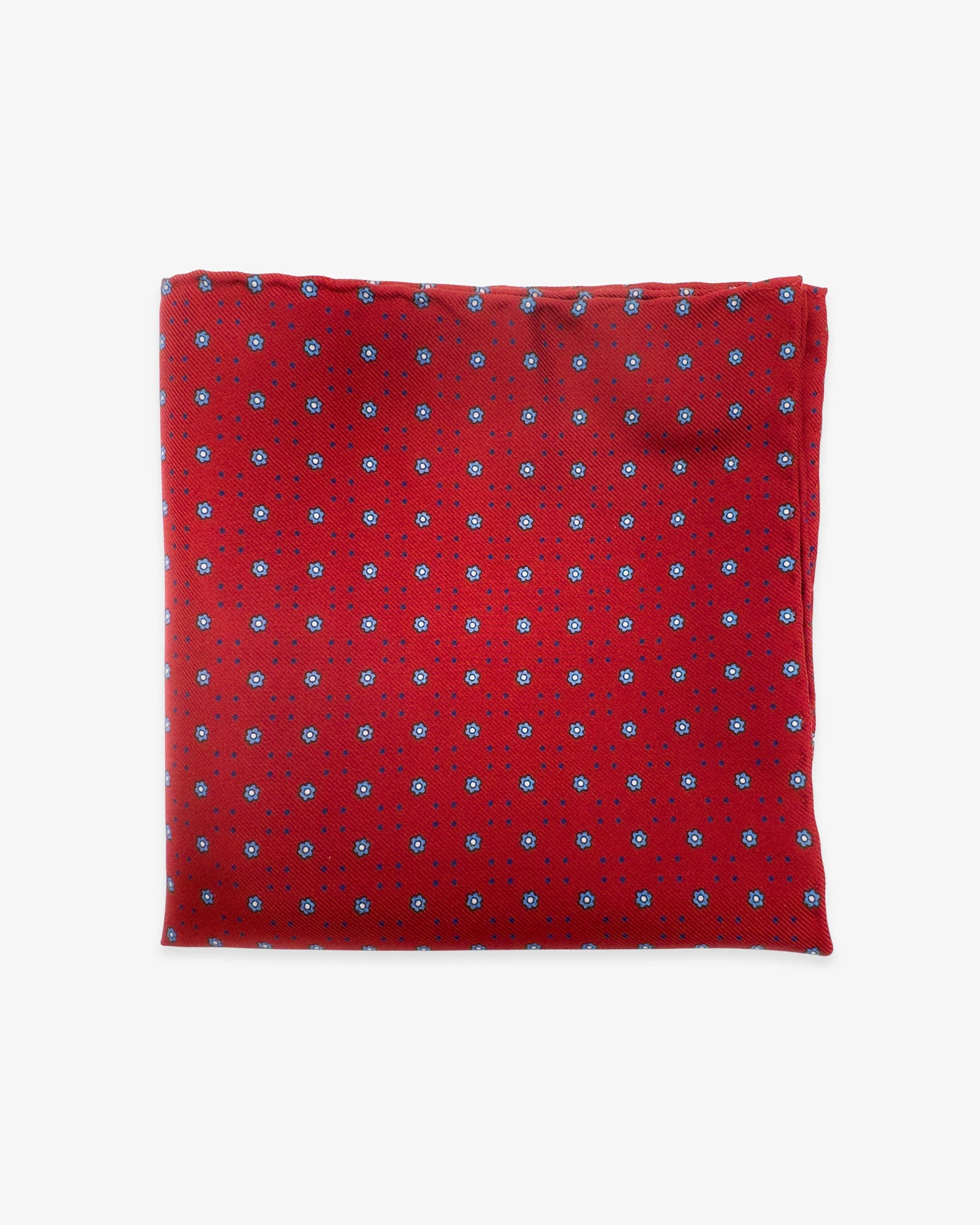 The 'Studley' silk pocket square from SOHO Scarves UK collection. Folded into a quarter, showing the tiny blue floral patterns and dots against a red background.