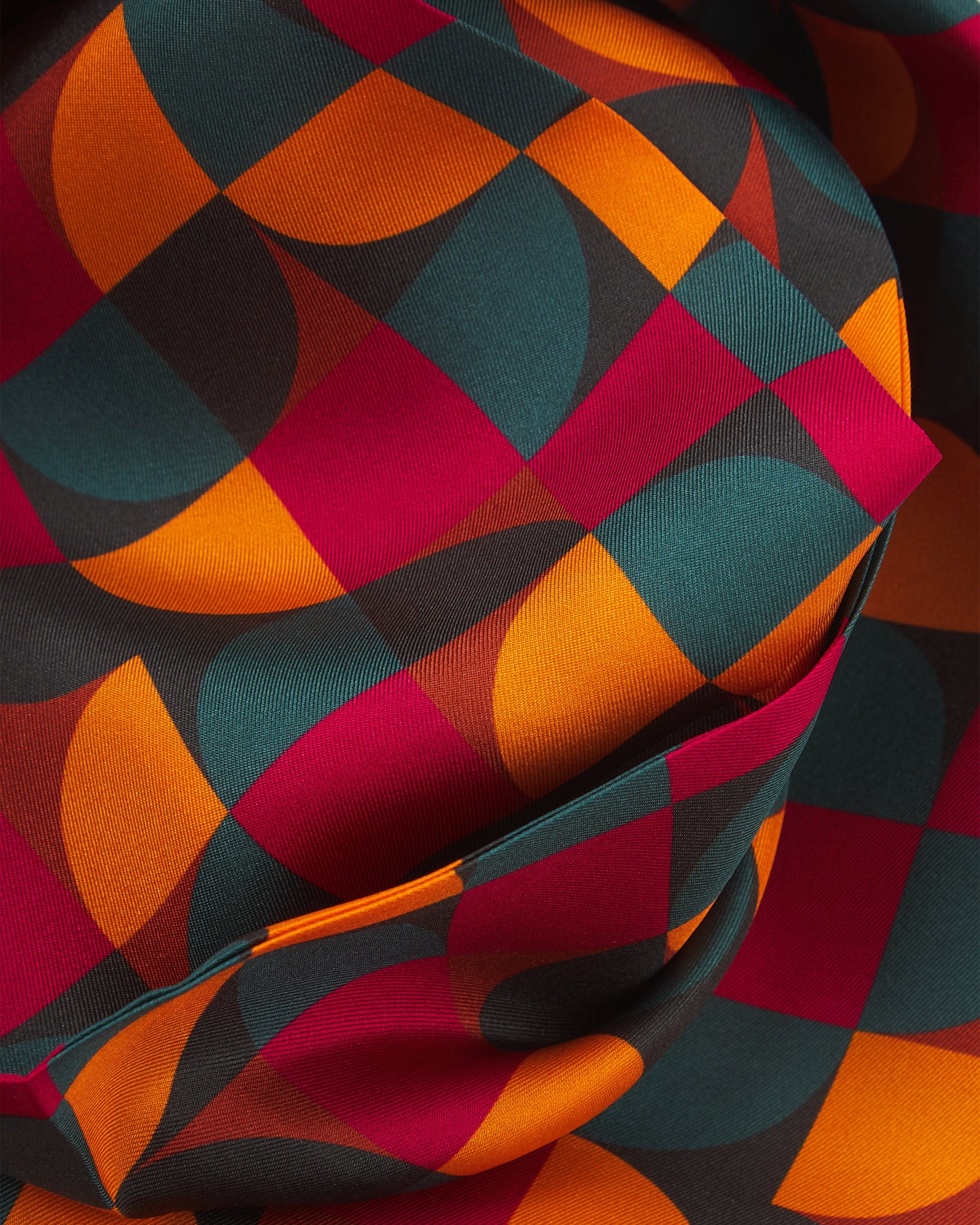 A ruffled close-up of the 'Stuttgart' silk scarf, presenting a closer view of the multicoloured, Bauhaus inspired patterns.