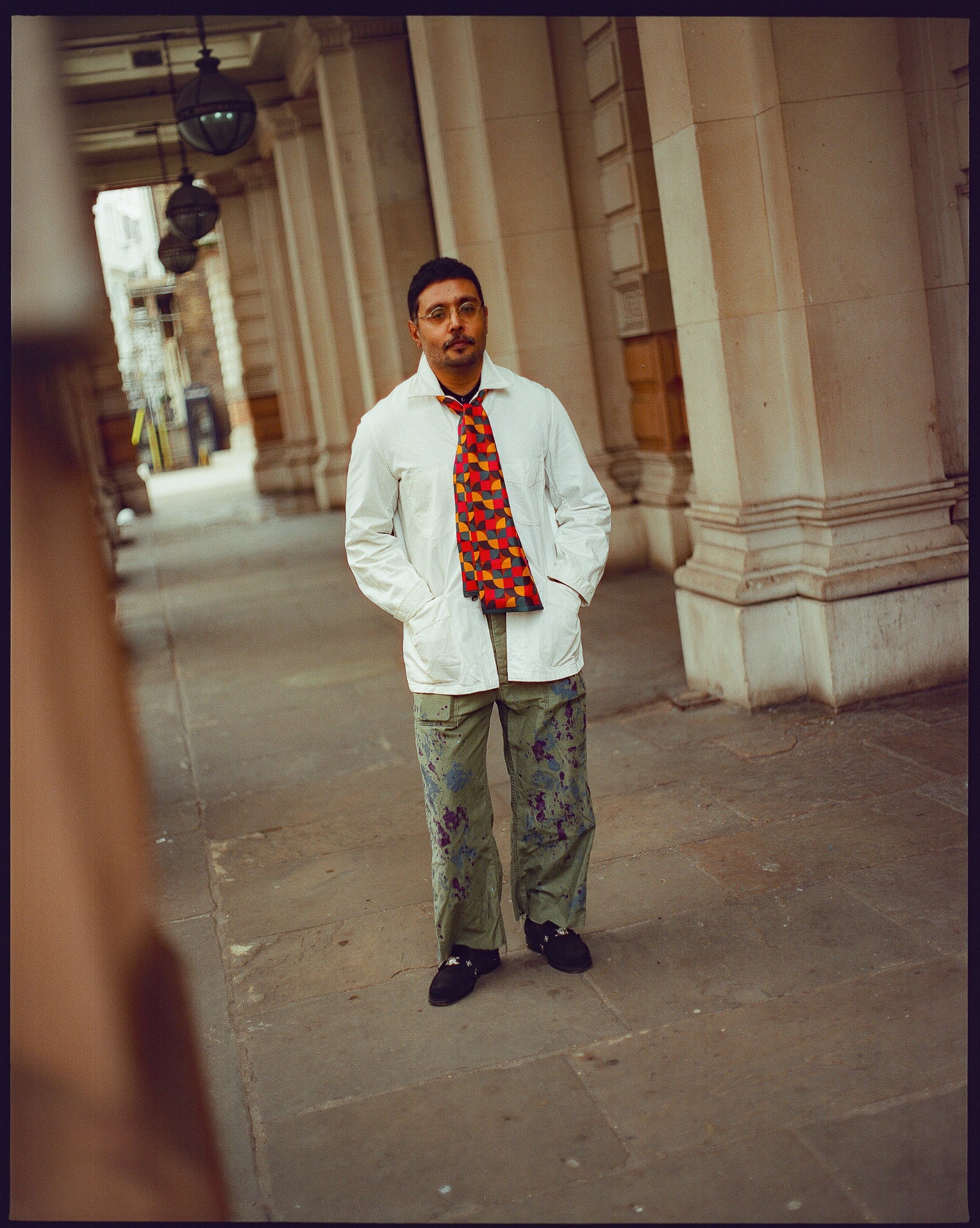 Man wearing a white jacket and cargo pants wearing the colourful 'Stuttgart' silk scarf from SOHO Scarves.
