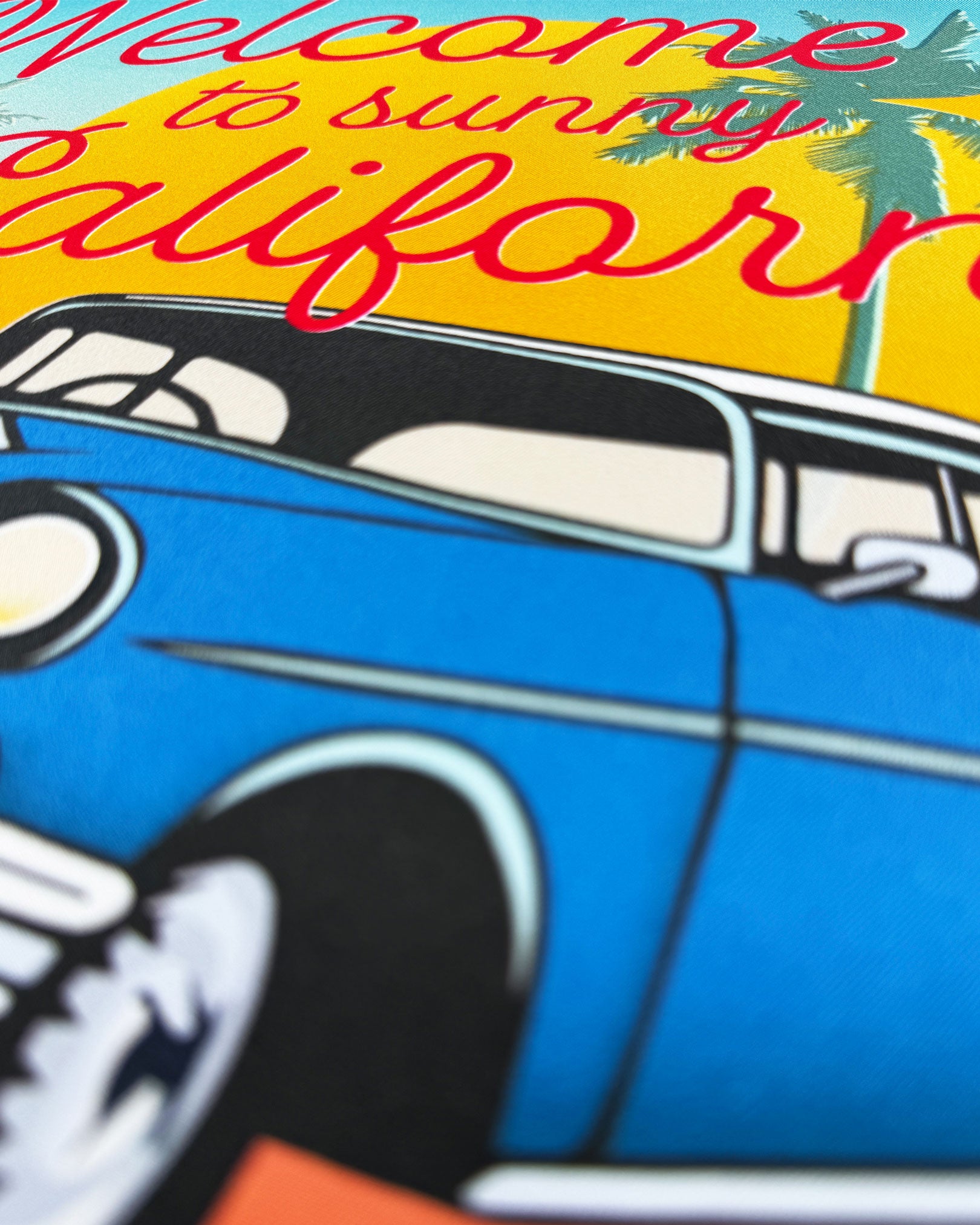 A close-up of the 'Sunset Ride' blue silk headscarf, presenting a closer look at a portion of the blue Cadillac.