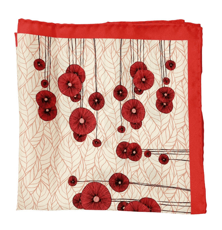 The 'Thames' silk pocket square from SOHO Scarves folded into a quarter, showing the red poppy flower pattern.