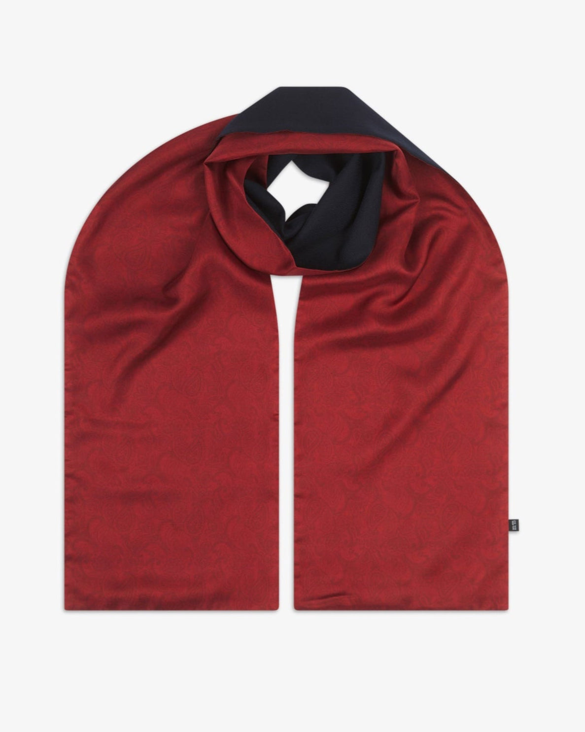 The 'Tonal Paisley' cranberry wool-backed silk scarf, looped in the centre to display the rich red paisley silk surface and the dark wool underside curling through at the neckline.