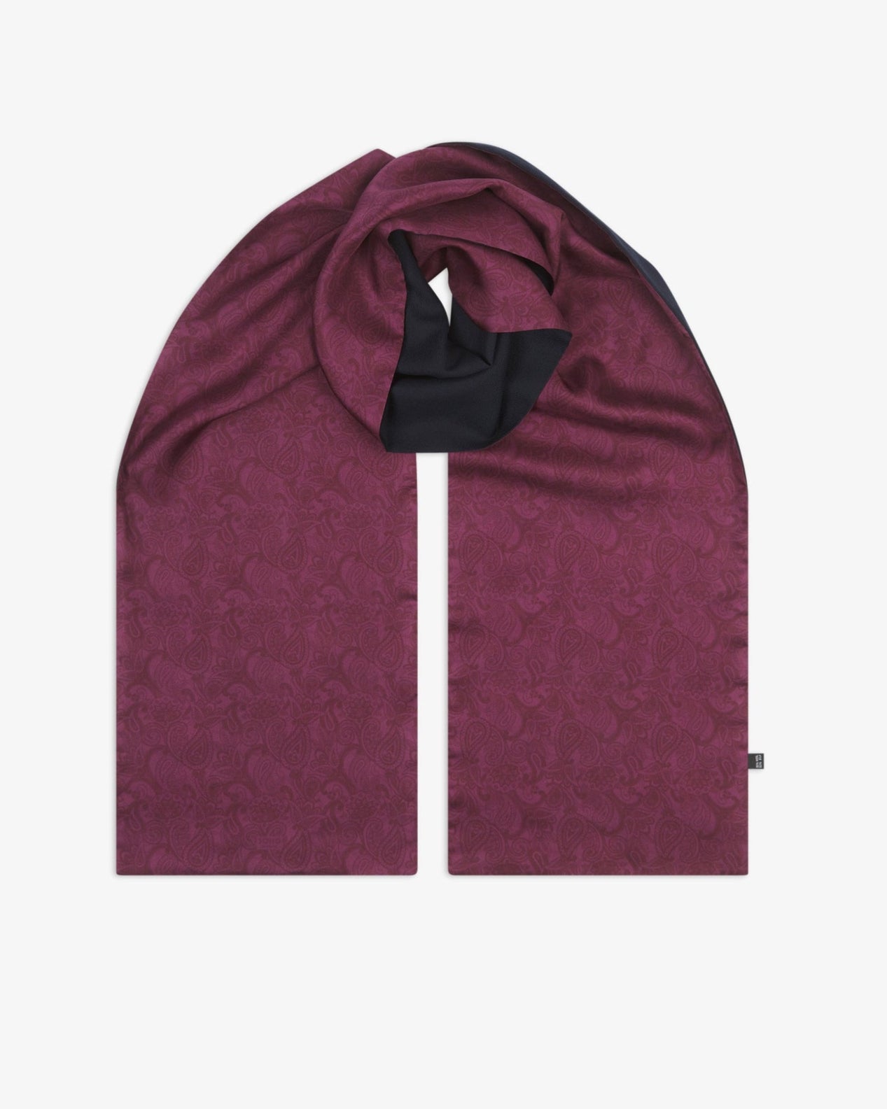 The 'Tonal Paisley' purple wool-backed silk scarf, looped at the centre to show the length of the plum paisley silk fabric, with the soft black wool underside subtly exposed at the loop.