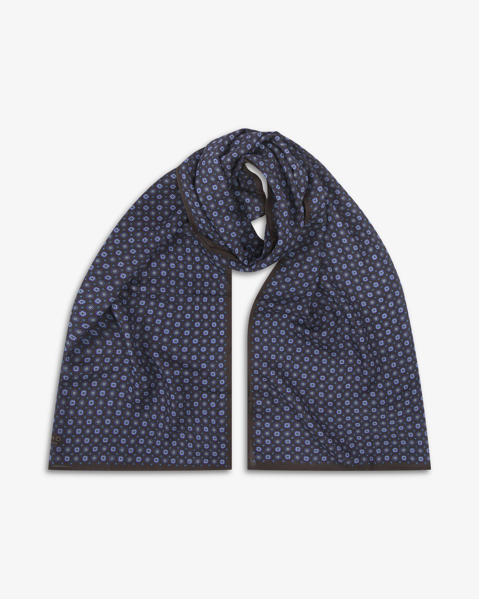 The Toshima 'Mahogany Daze' bohemian wide scarf looped with both ends parallel, showcasing small stylised floral motifs in purple and blue on a rich mahogany brown background across the soft modal and wool blend fabric.