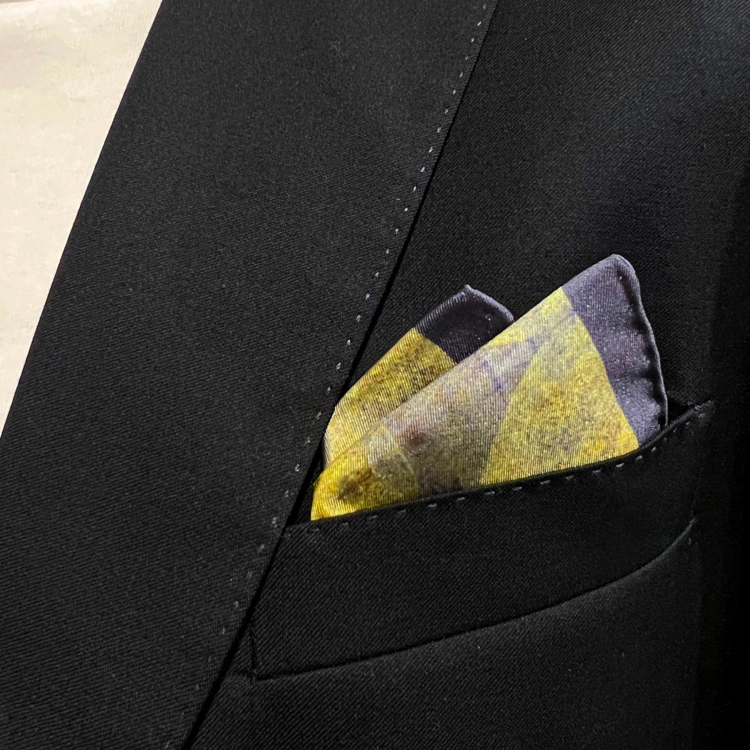 Silk square handkerchief with yellow and purple textured effect. Placed in a jacket breast pocket.