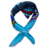 Blue version of the BT Tower multicoloured pattern neckerchief twisted and curled into a loop and placed on a white background.