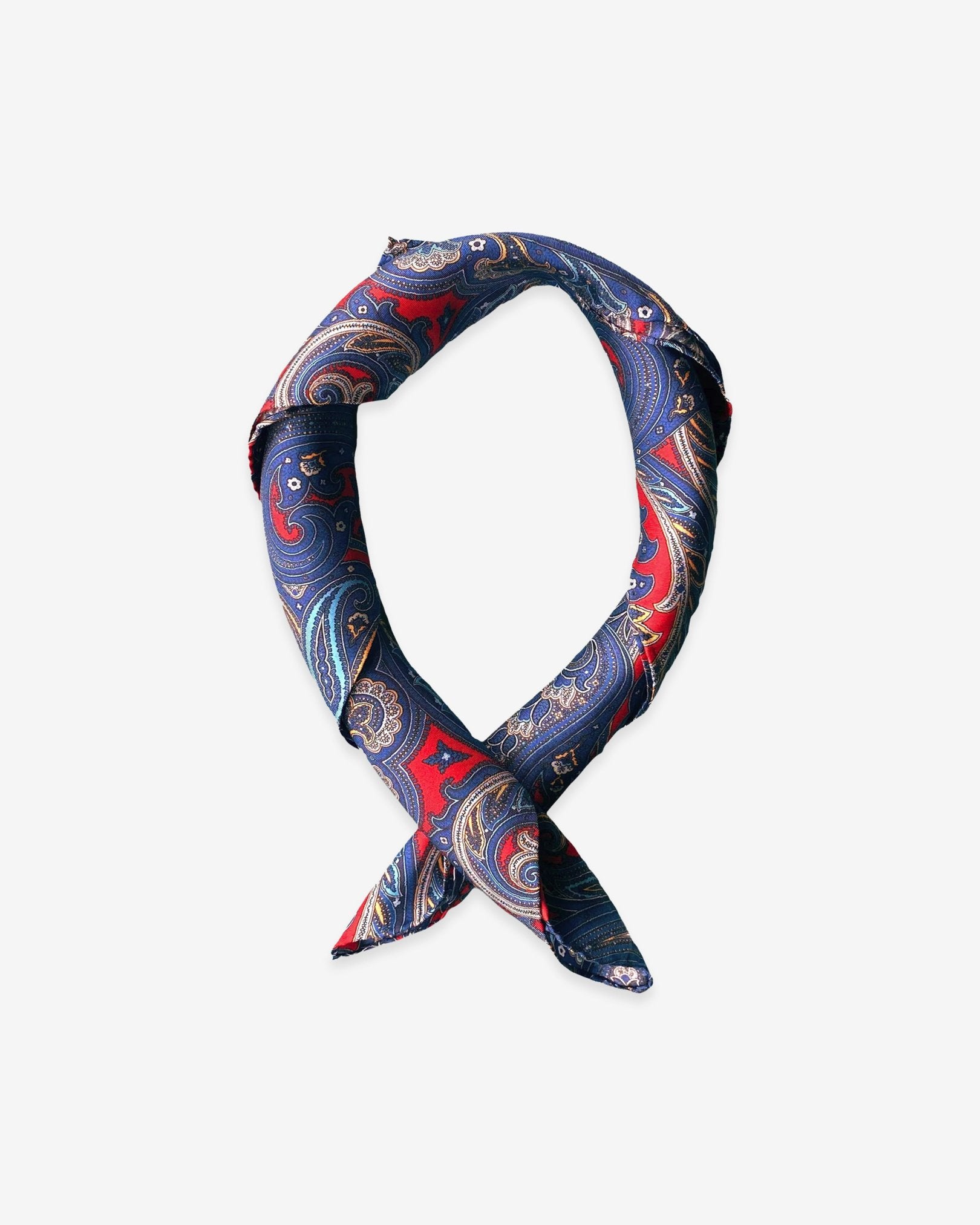 Square scarf rolled into a loop, showing the sheen of the fabric and the striking deep-red and blue contrasts.