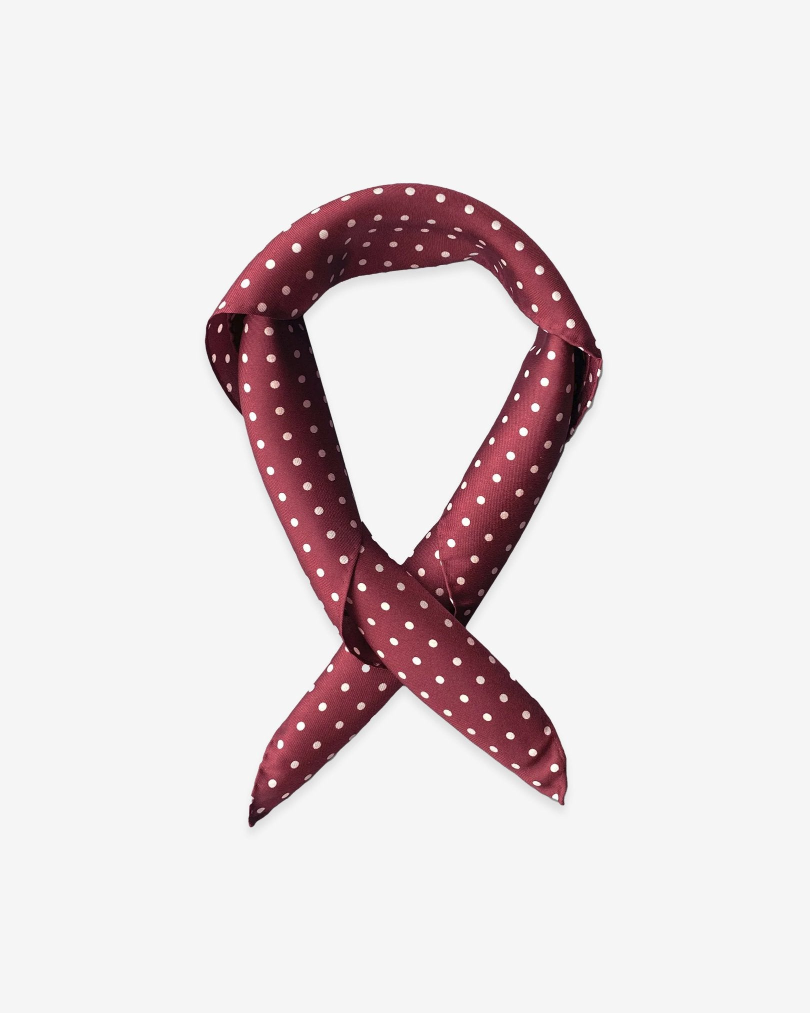 Square scarf rolled into a loop, showing the timeless white polka-dot pattern on a maroon background.