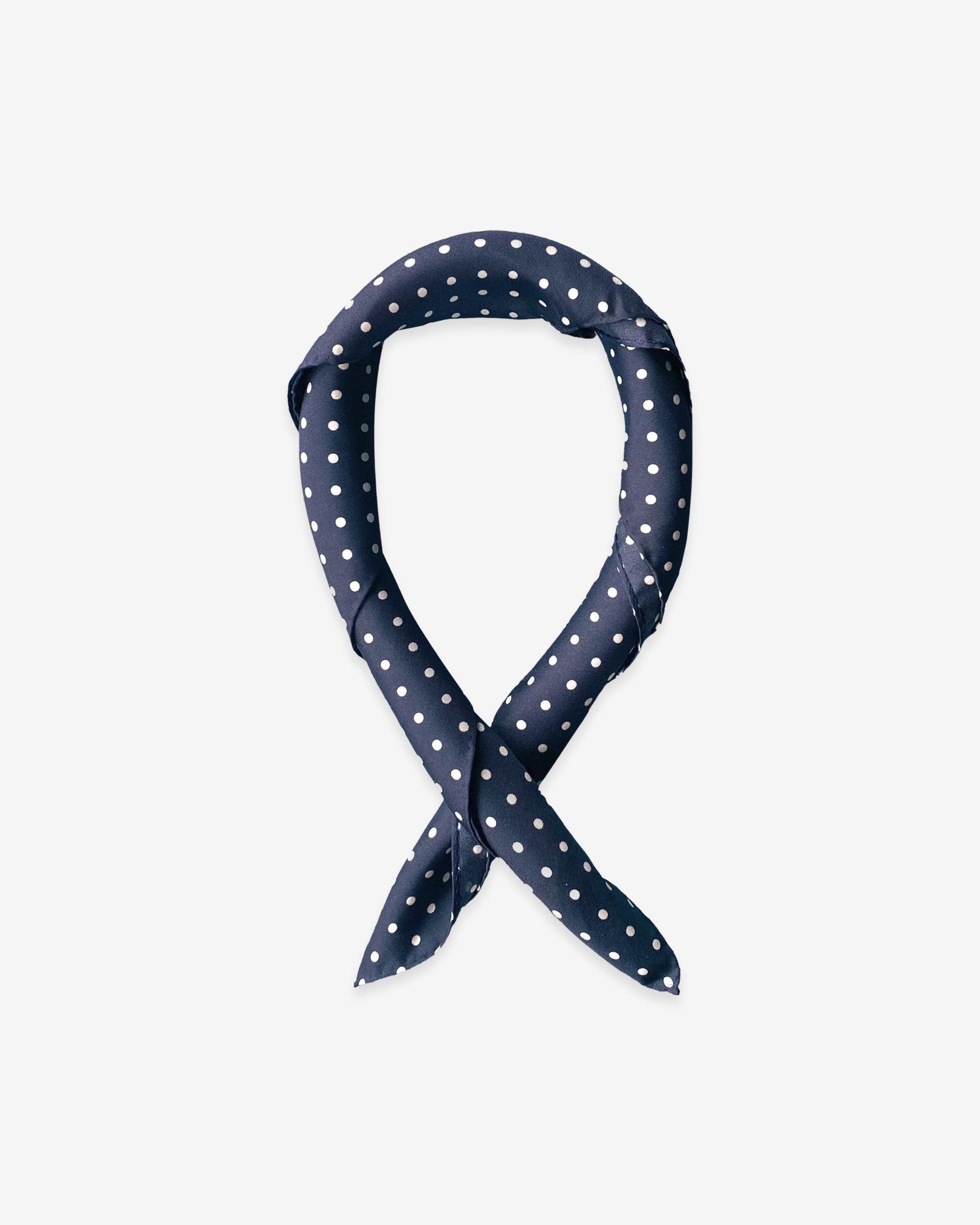 Square scarf rolled into a loop, showing the fabric sheen of the classic dark-blue and white spotty silk fabric