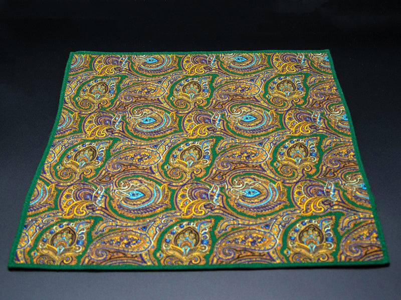 Full, unfolded flat view of 'The Kingly' wool pocket square, clearly showing the extent of the repeats of the paisley and gold, green and brown patterns.