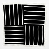 Completely unfolded silk pocket square showing the entirity of the striped monochrome patterns. Alternating white stripes at 90 degree intervals on a black background.