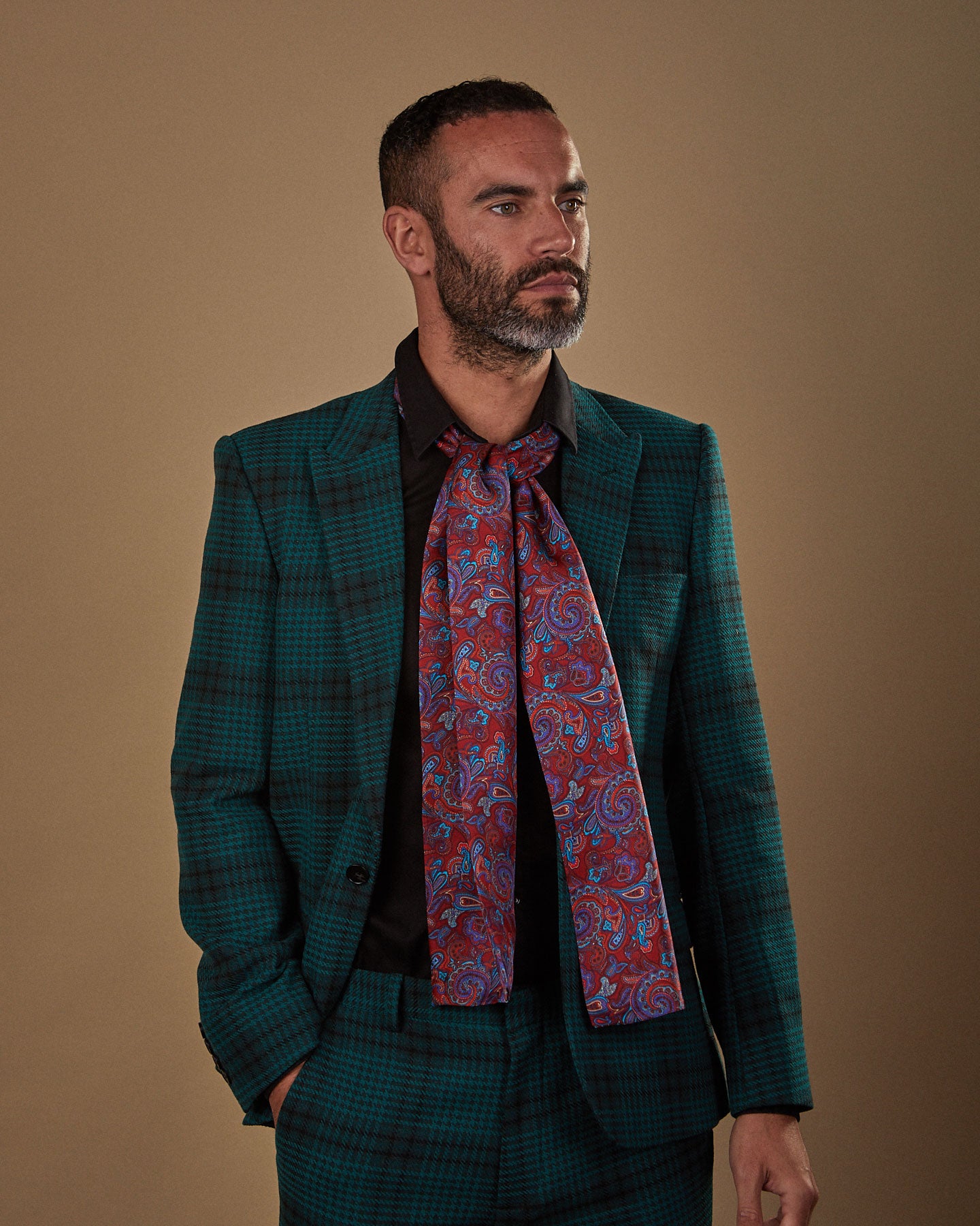 Front view wearing a 'Bretton' paisley silk scarf from SOHO Scarves, paired with a black shirt and deep green chequered suit.