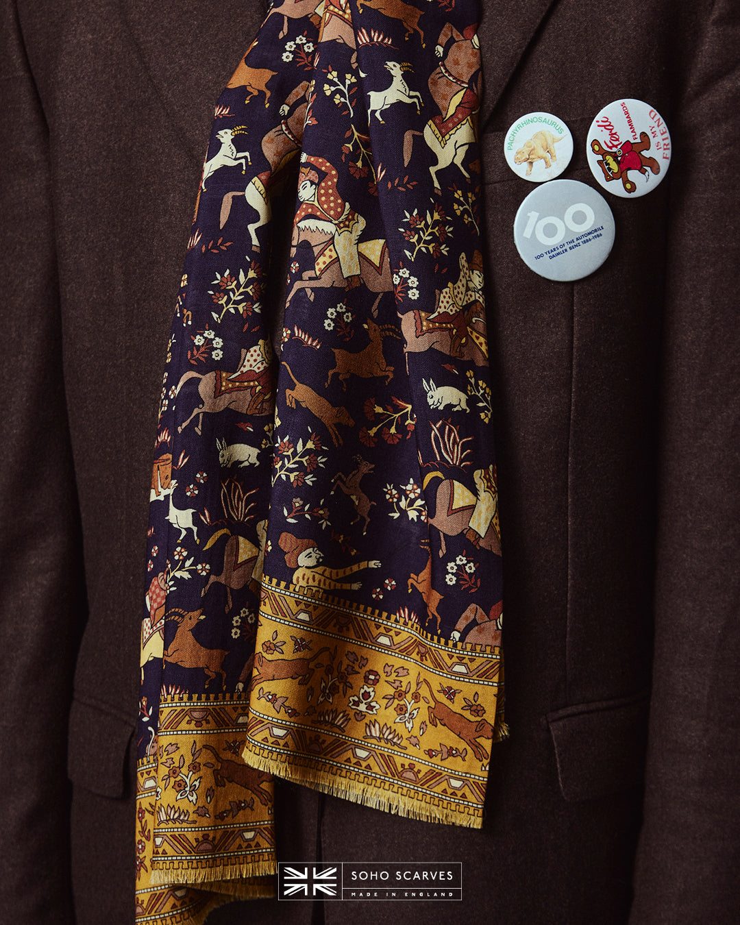 Close-up wearing the English-made, 'Hunters in Indigo' silk and wool scarf, with focus on the blue, brown, and yellow design, combining ancient East Asian hunting motifs.