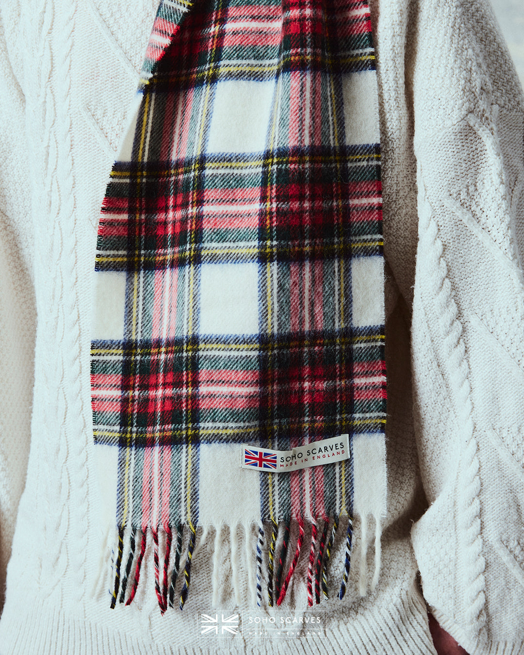 Close up of man wearing the Yorkshire-made, 'Highlands Tartan Dress' scarf, with focus on the 'Soho scarves, Made in England' label and matching fringes.