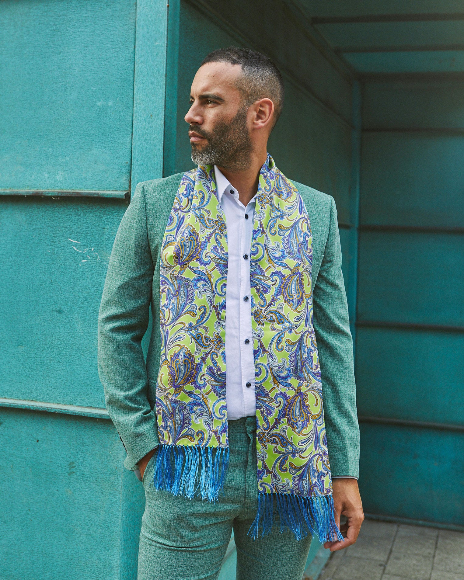Man wearing the silk 'Daytona' aviator scarf draped around neck paired with casual mint-green suit.