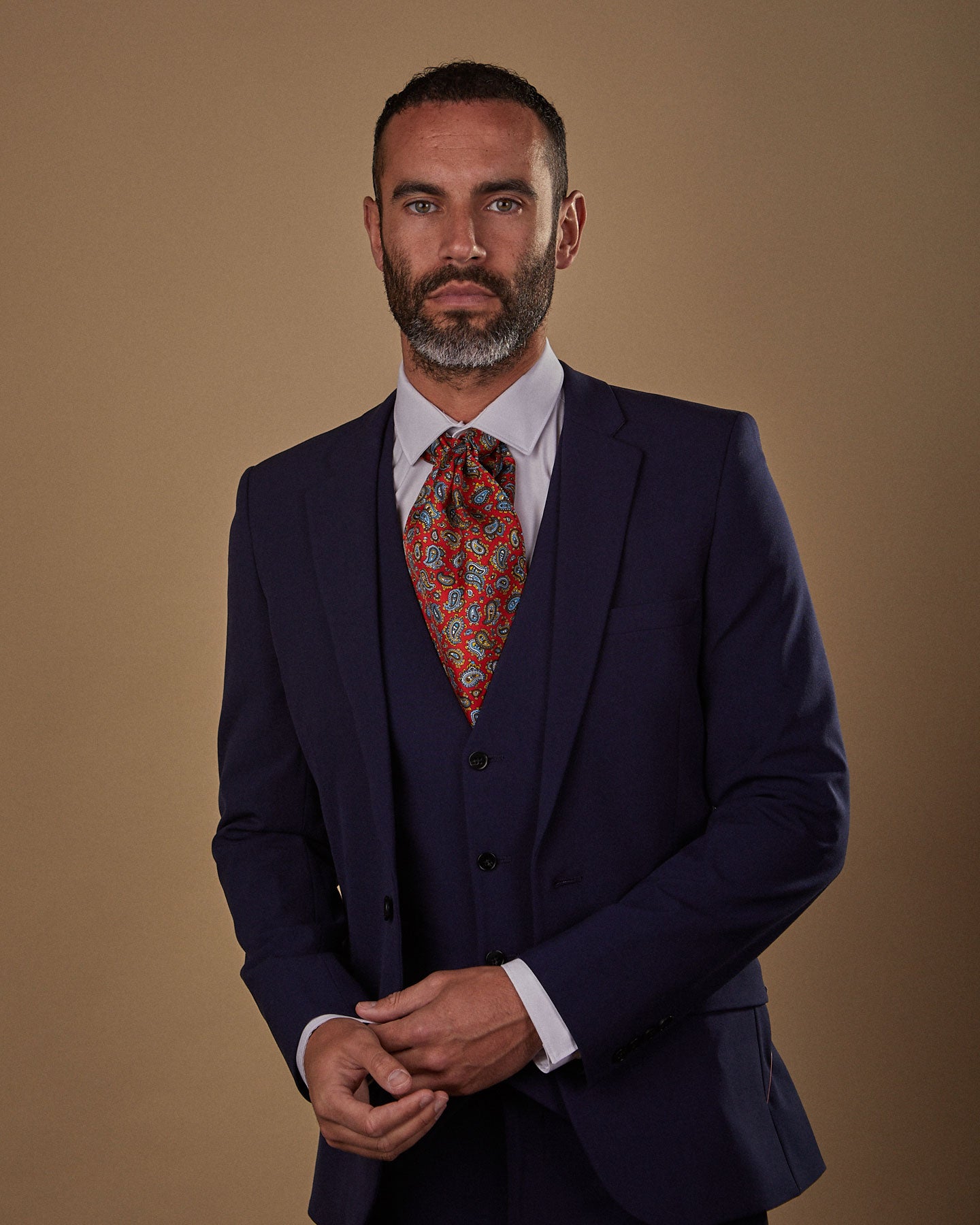 Front view from waist-up, wearing a 'Shinjuku' silk Double Ascot tie from SOHO Scarves, paired with white shirt and three-piece midnight blue suit.
